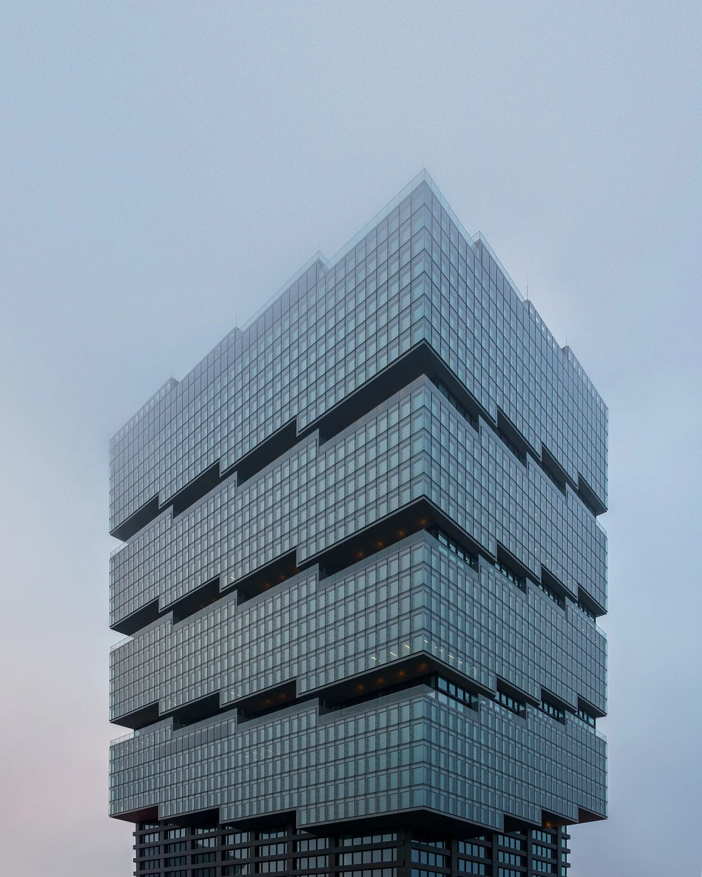 Edge East Side Tower, Berlin: Modern skyscraper featuring a stacked, geometric design and a glass facade, shrouded in fog. Contemporary architecture in Berlin.
