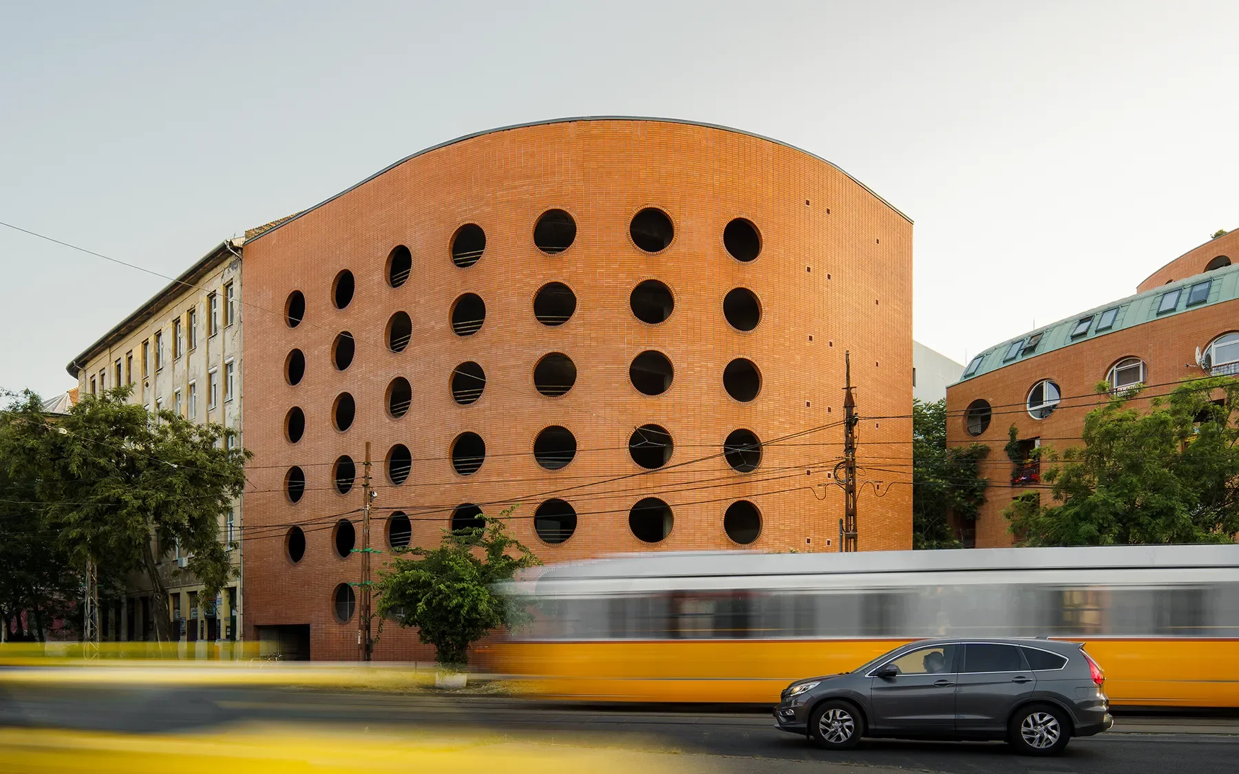 Side view of Orczy Tér Budapest apartment block with circular openings and city traffic