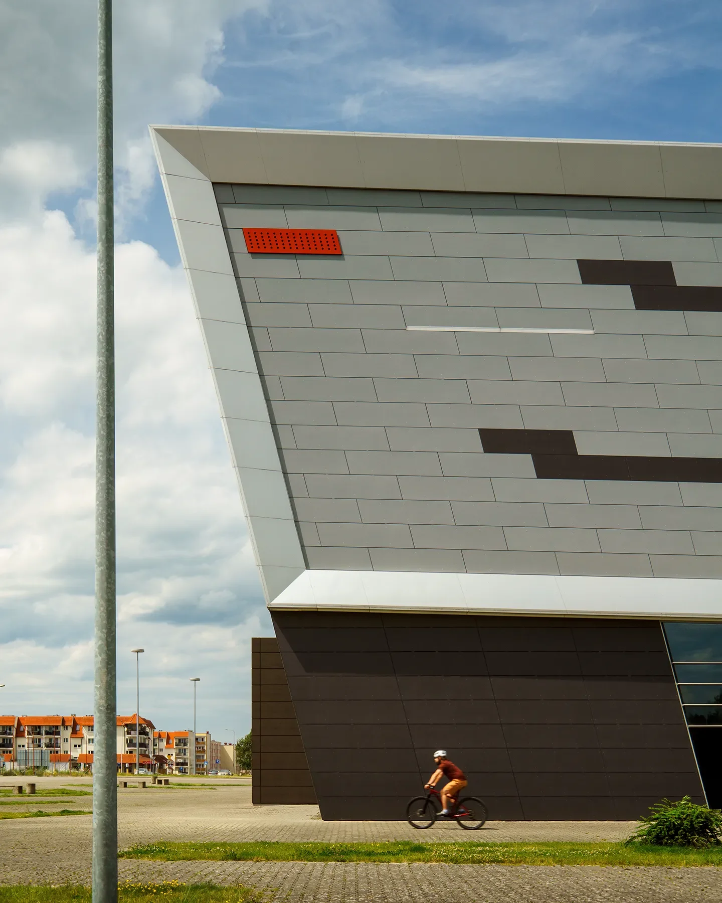 Architectural side crop of Koszalin Sports and Entertainment Arena with person visible for scale against the metal facade