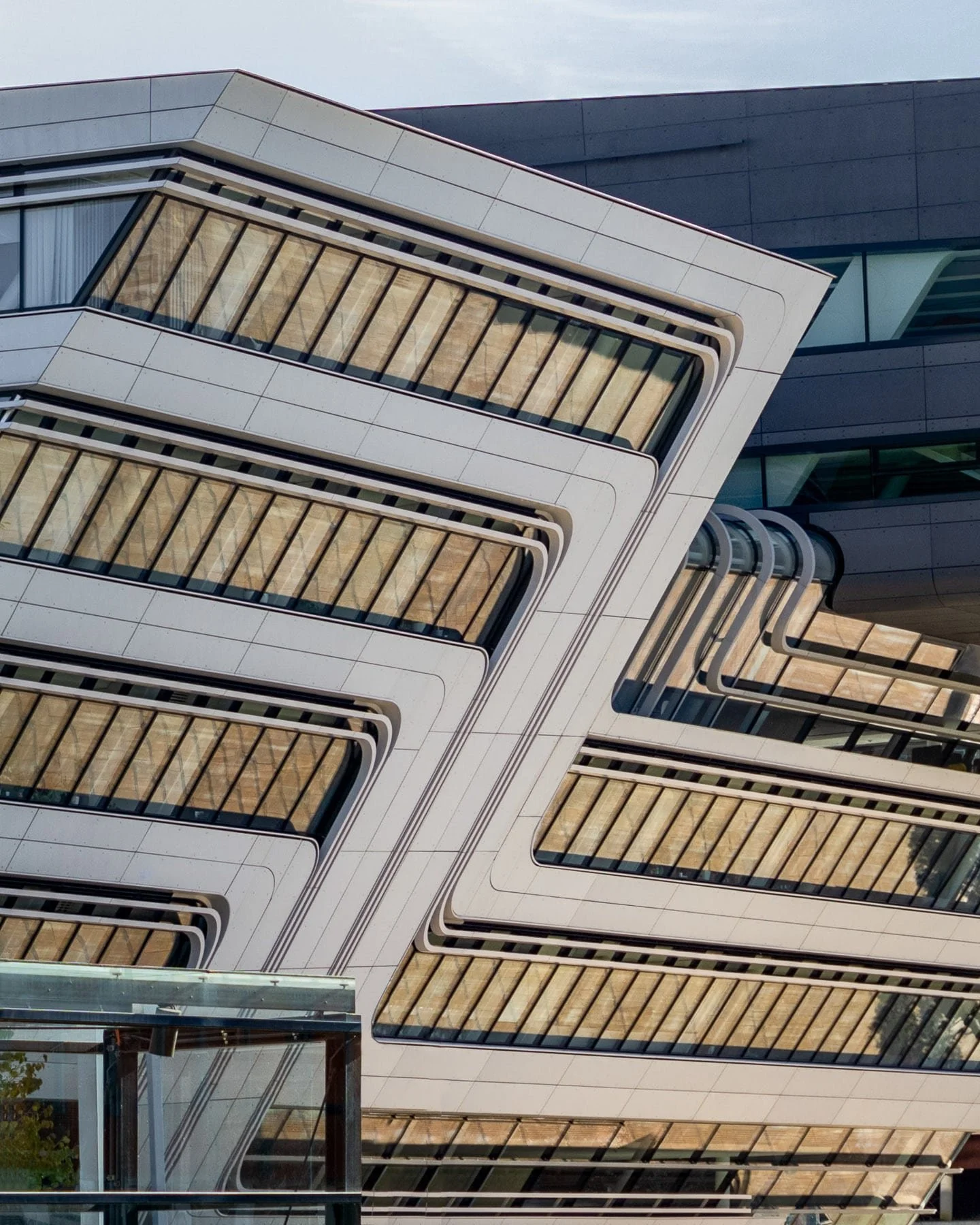 Modern architecture in Vienna: Detailed view of the WU (Vienna University of Economics and Business) Library & Learning Center, Zaha Hadid Architects, featuring its distinctive, geometric shape, layered elements, and reflective glass surfaces. 