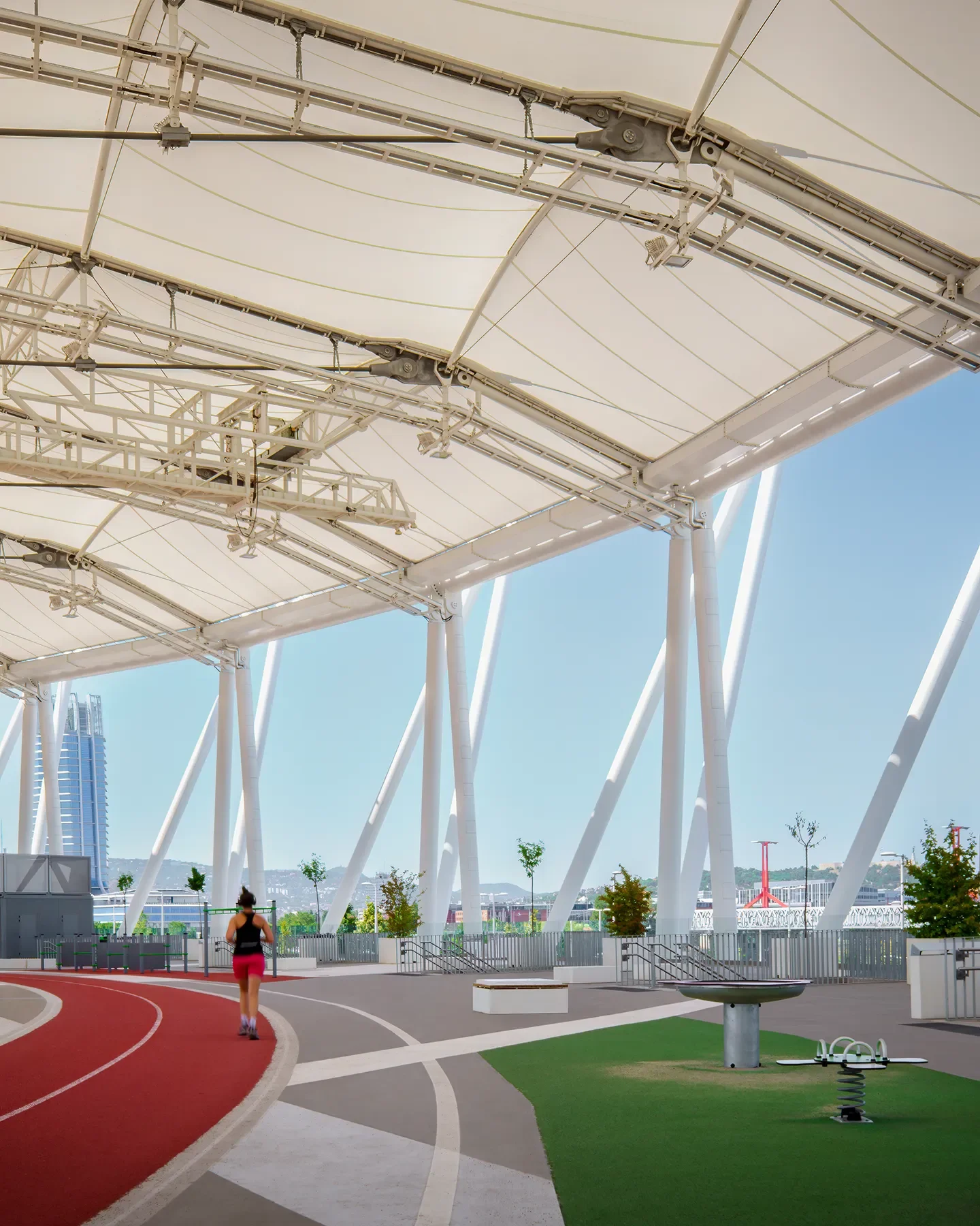 First-level view of Budapest Athletics Stadium public track with person running in shadow at midday