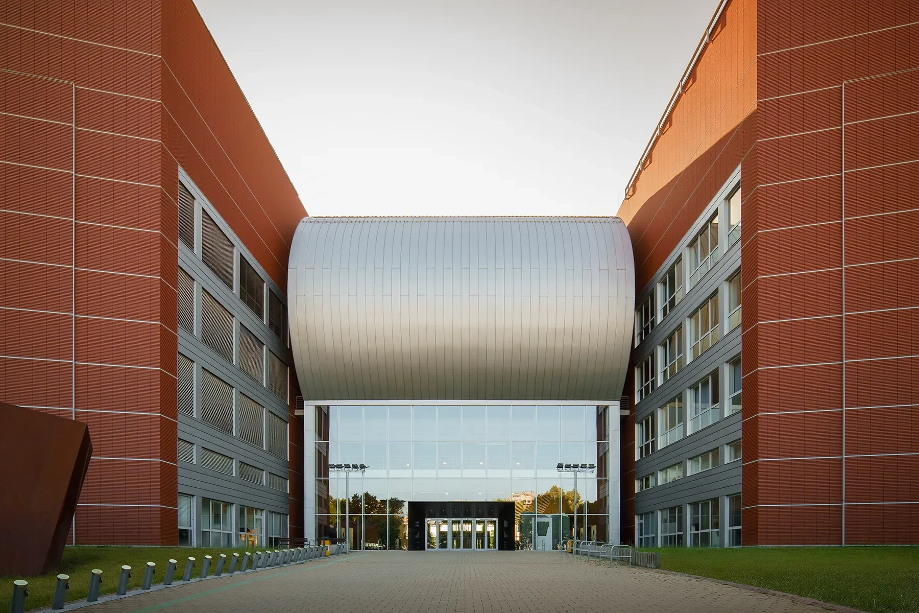 Front facade of BME Q Building at Infopark Budapest in morning shadow, large windows and central metal roof