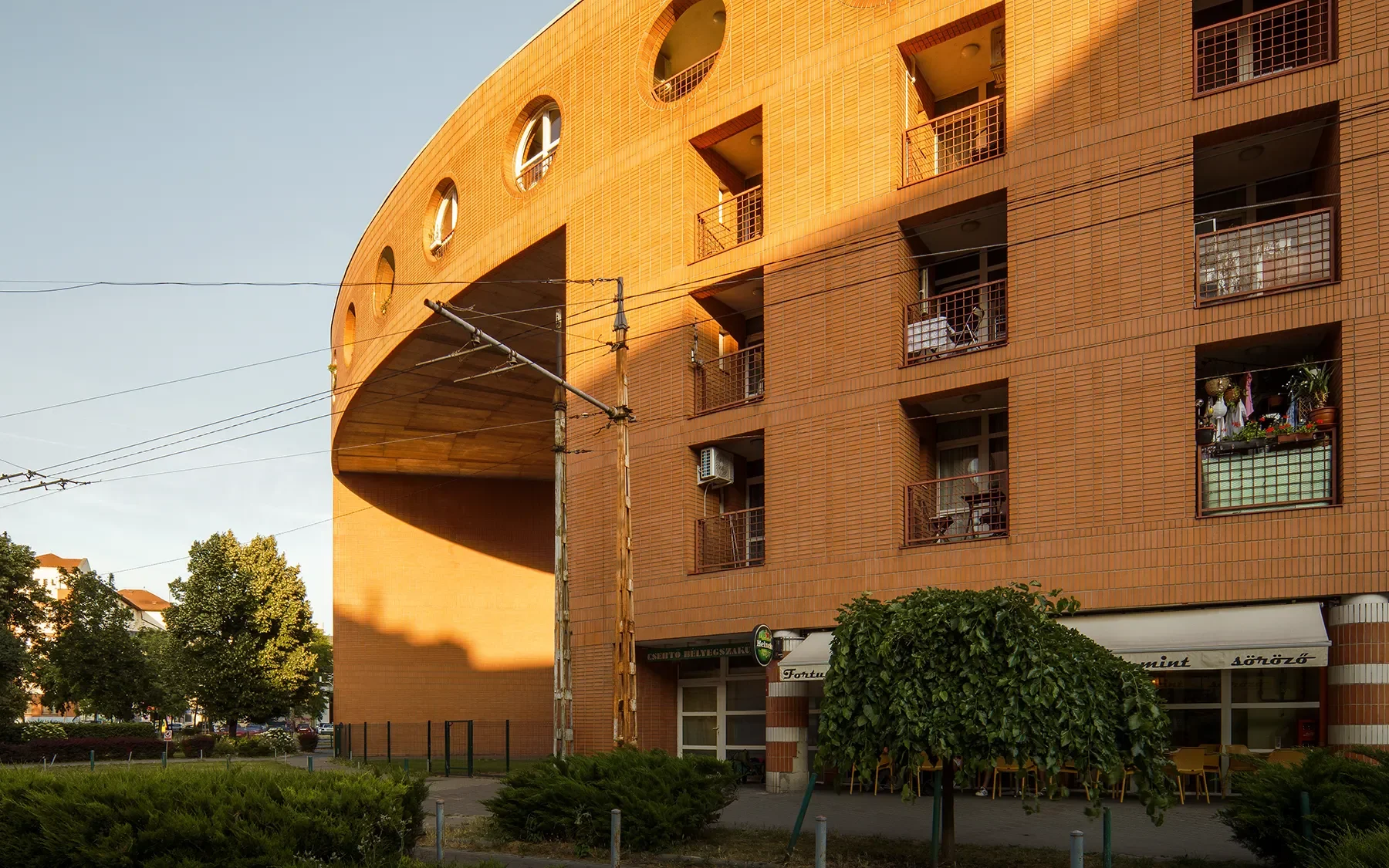 Close-up side view of Orczy Tér Budapest entrance arch highlighting curve and greenery