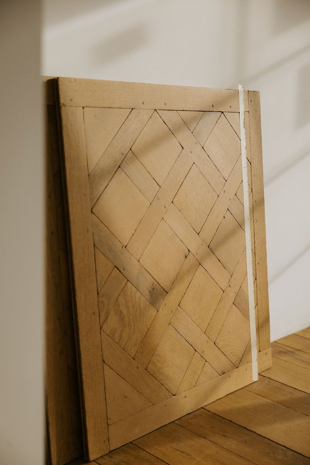Wooden door with a basket weave pattern leaning against a wall.