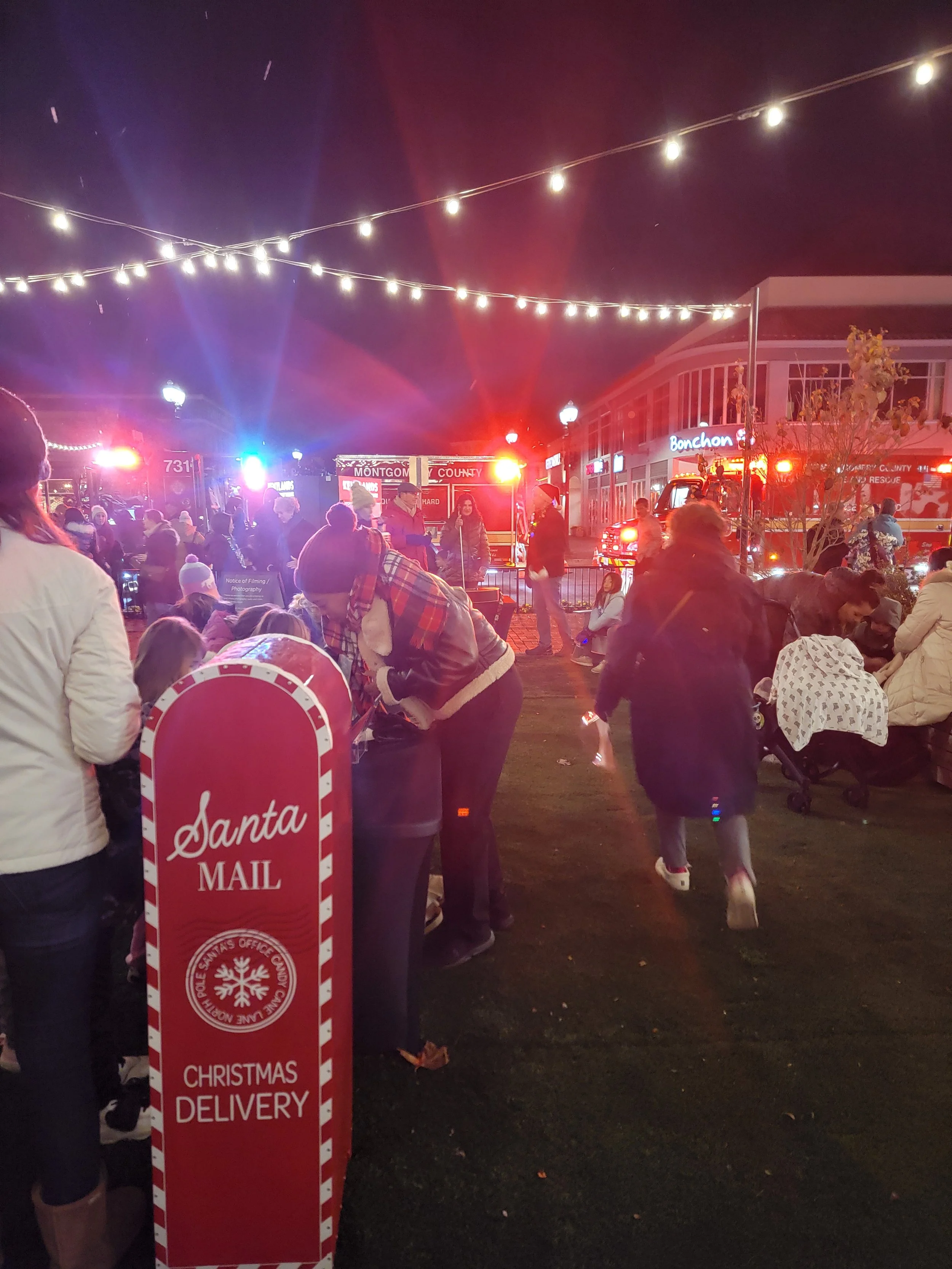 People standing near a mailbox for letters for Santa at the Tree & Menorah Lighting