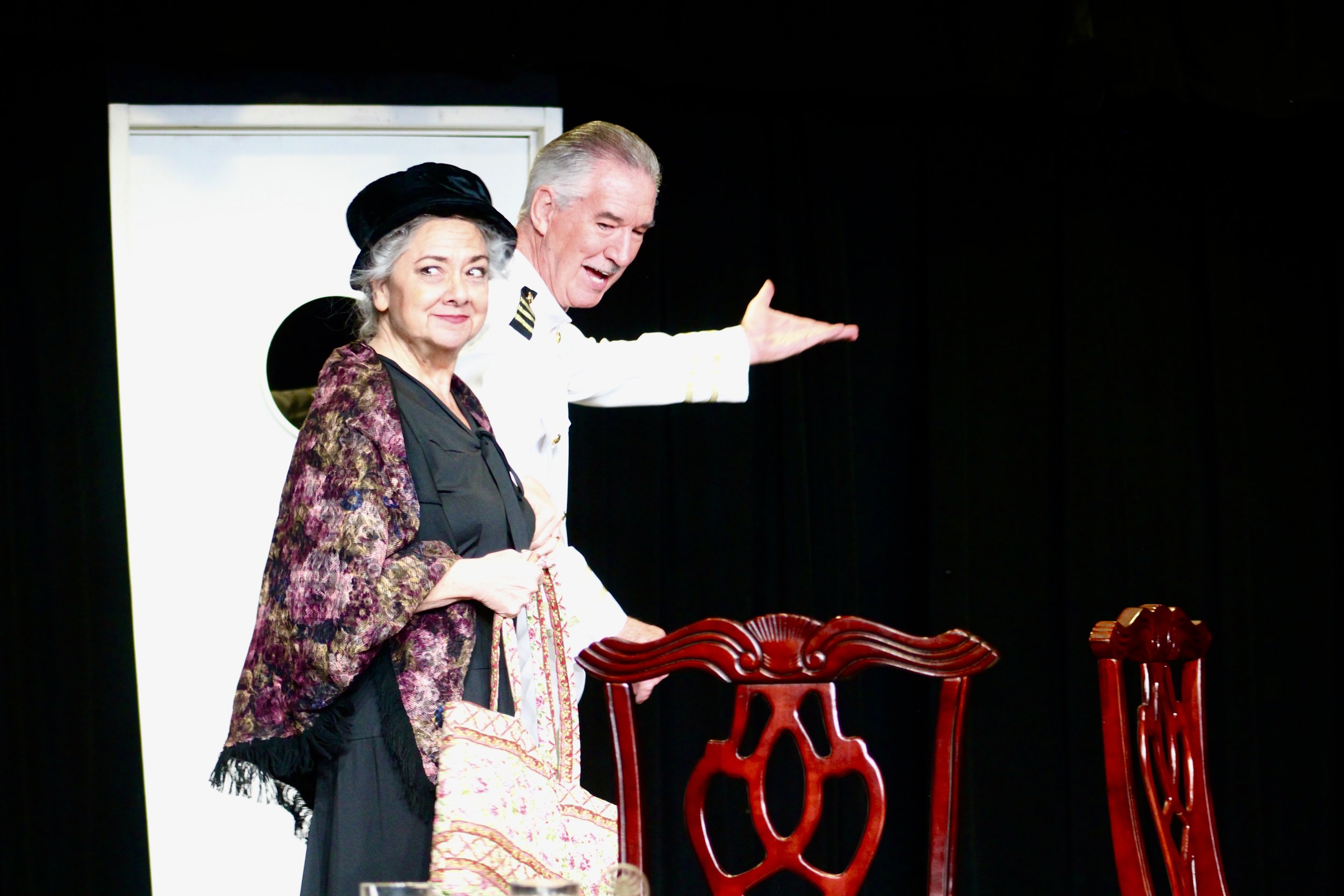 A ship captain directing a woman to go ahead of him in the Kentlands Community Players' production of 'Outward Bound'