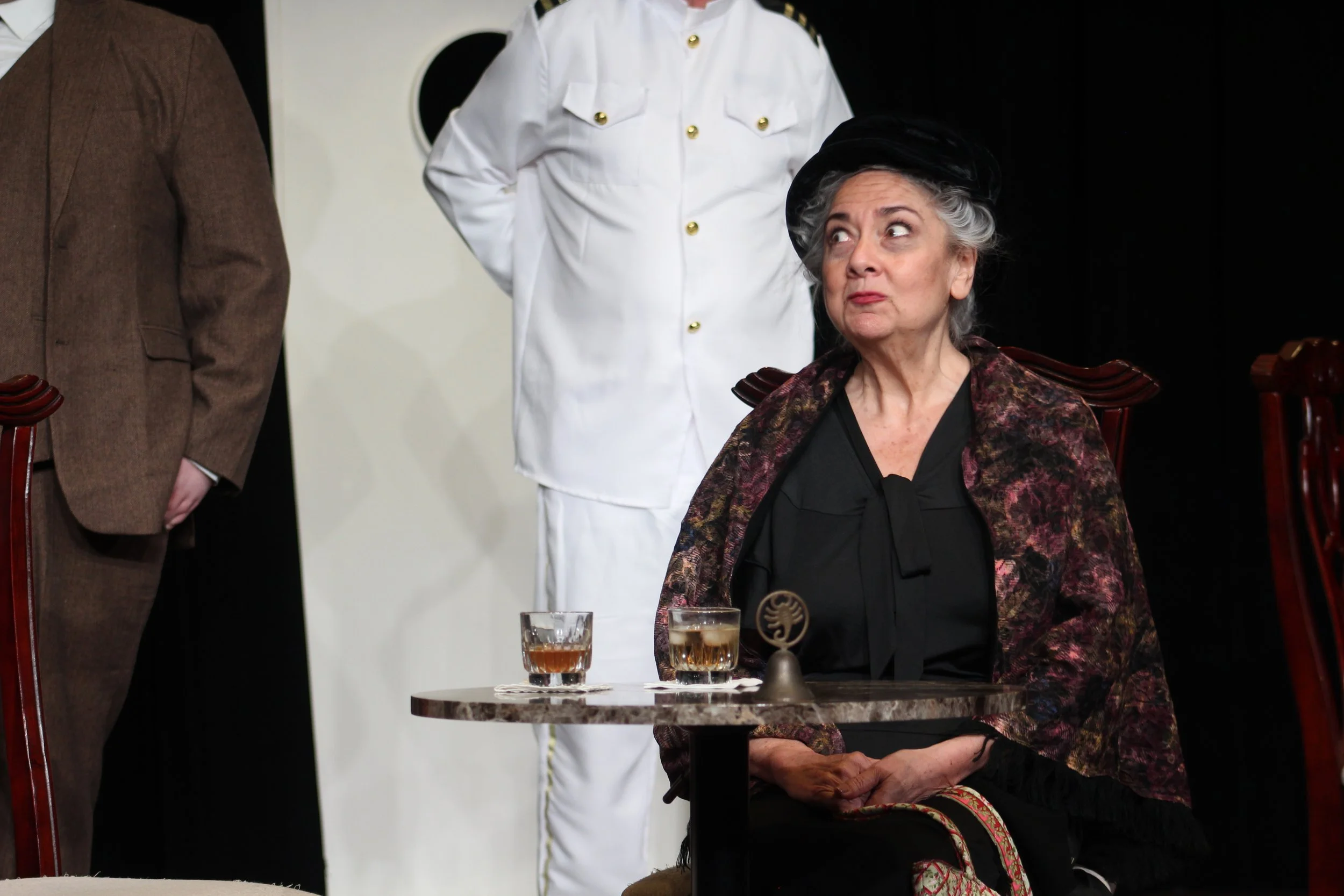 An elderly woman sitting at a table in the Kentlands Community Players' production of 'Outward Bound'
