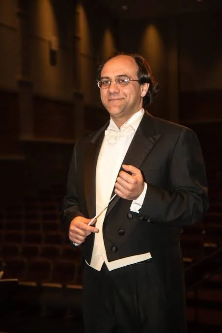 Maestro Simeone Tartaglione in a tuxedo holding a conductor's baton