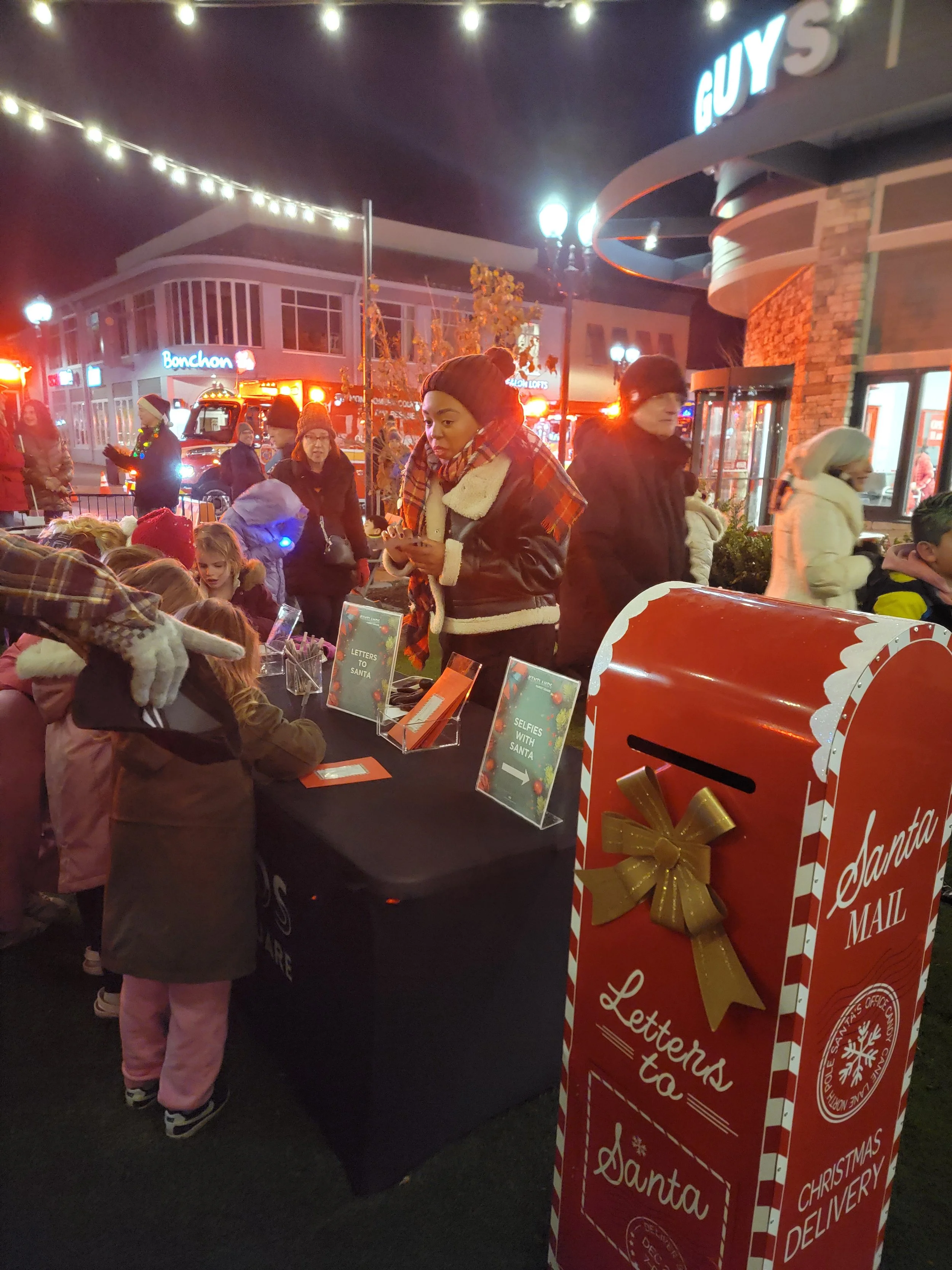 Children writing letters to Santa at the Tree and Menorah Lighting event next to a ‘Santa Mail’ mailbox