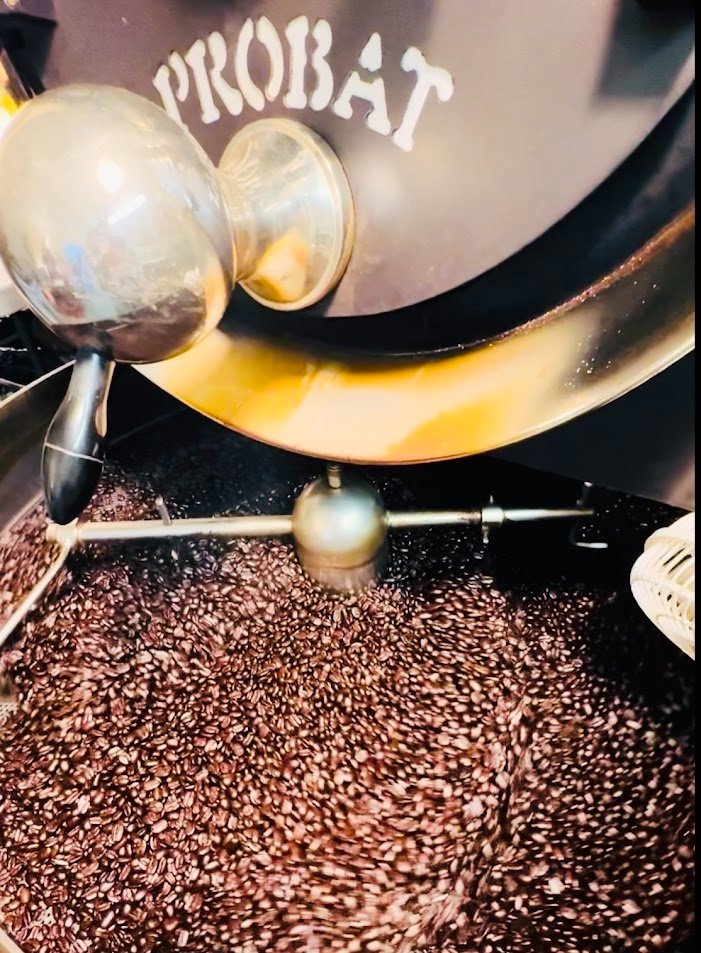 A coffee roasting machine with the word 'PROBAT' on it, roasting coffee beans.