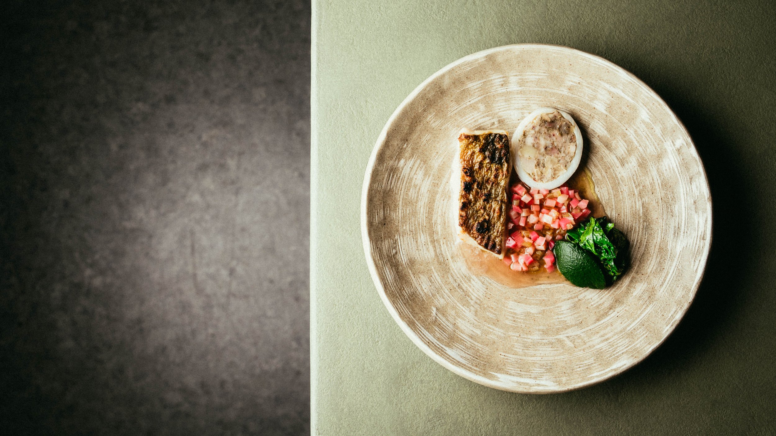 Fallachan Dining - Gourmet dish with grilled fish, diced vegetables, and leafy greens on a beige plate.