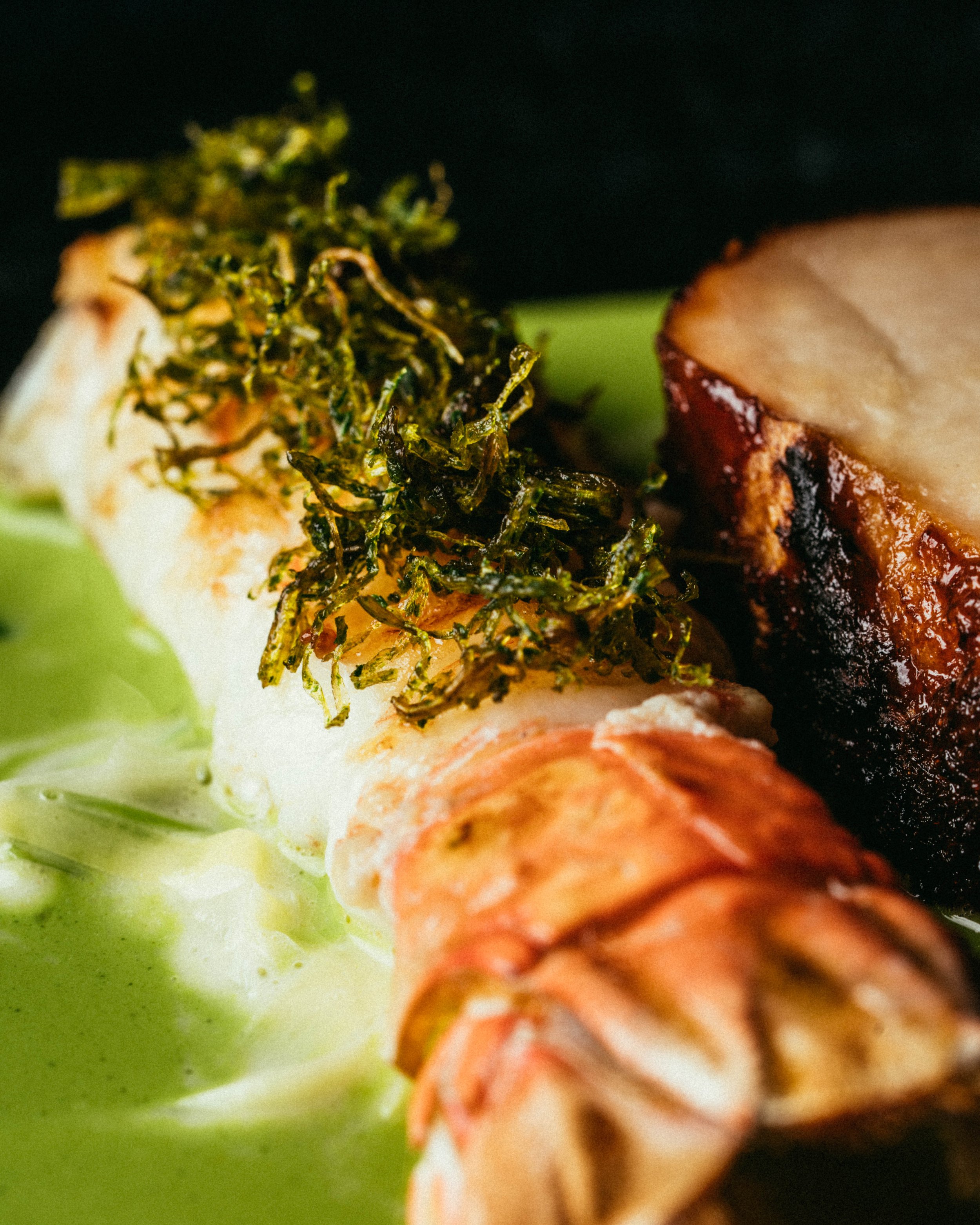 Fallachan Dining - Grilled lobster tail topped with fried herbs served with a slice of meat on a green sauce.