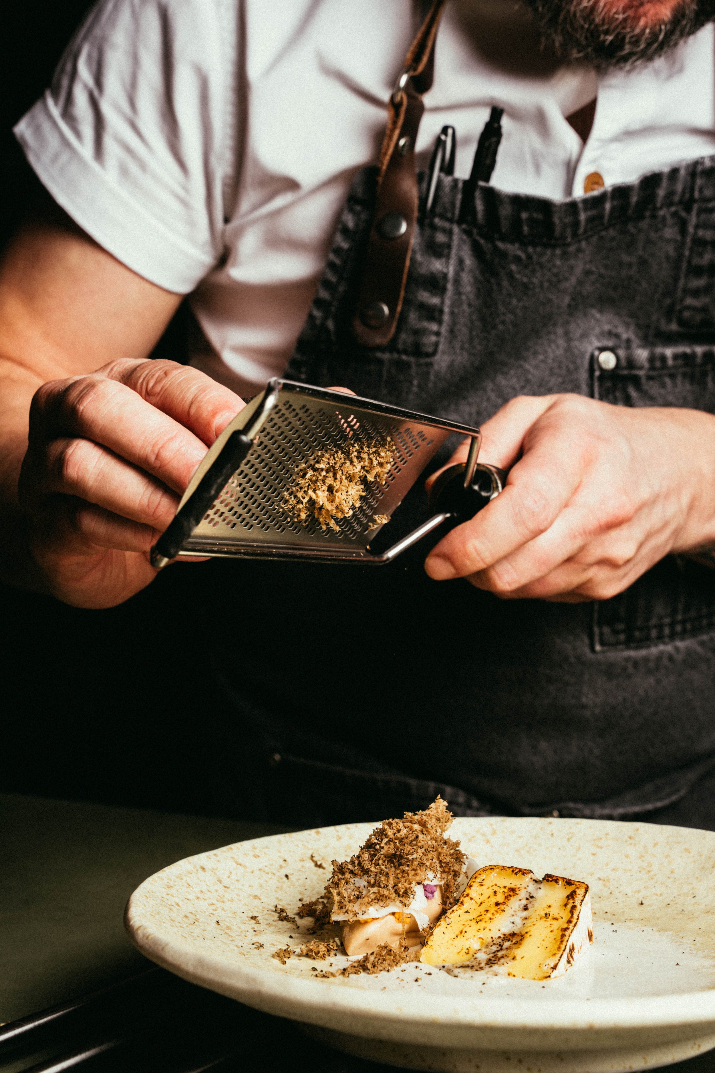 Fallachan Dining - Chef Craig Grozier grating truffle over a plated dish.