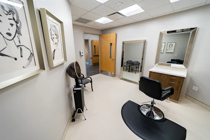 A hair salon or beauty parlor with a styling chair, mirror, and artwork on the walls.