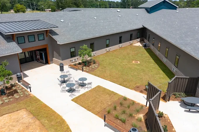 A bird's eye view of a courtyard with modern amenities, including seating areas and landscaped grass patches, surrounded by a gray building.