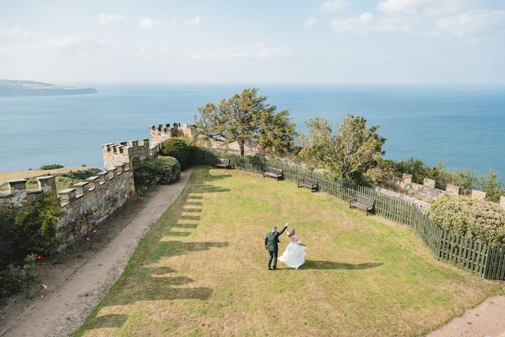 Couple dancing on the lawn overlooking the sea on their wedding day