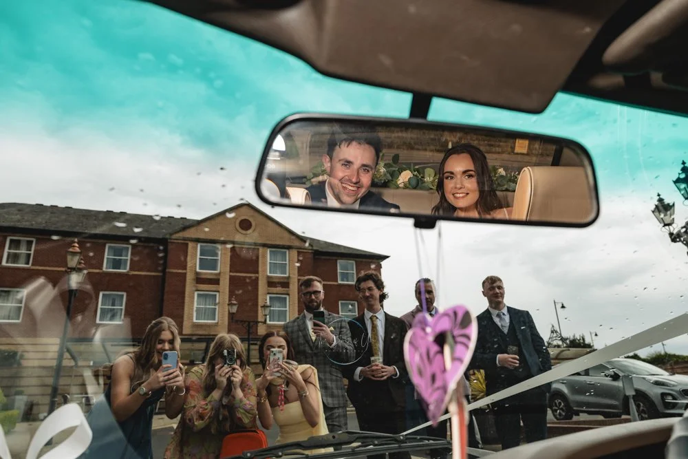 Wedding couple reflected in the mirror of a car
