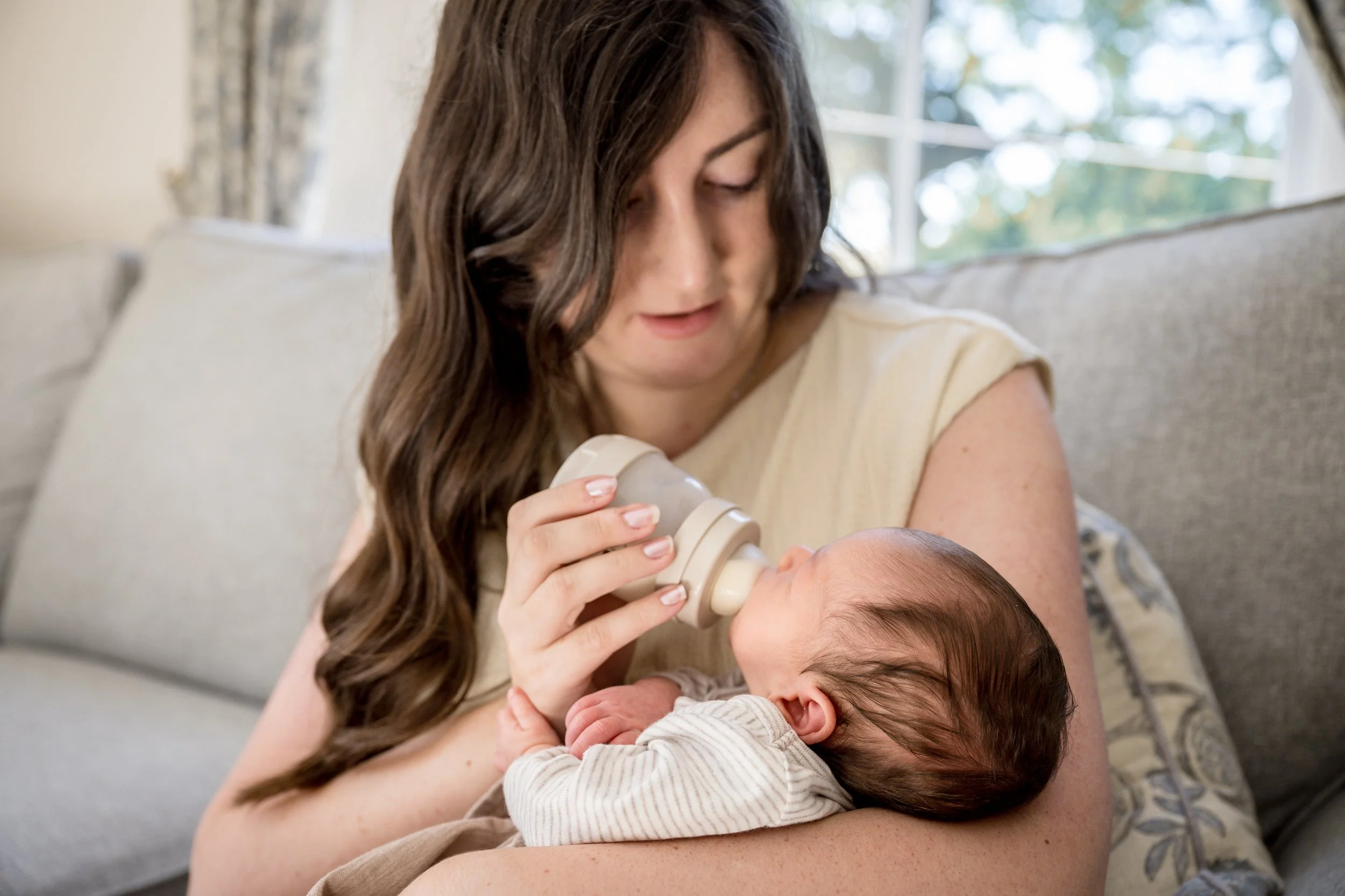 Mum feeding newborn baby at home during newborn lifestyle photosession