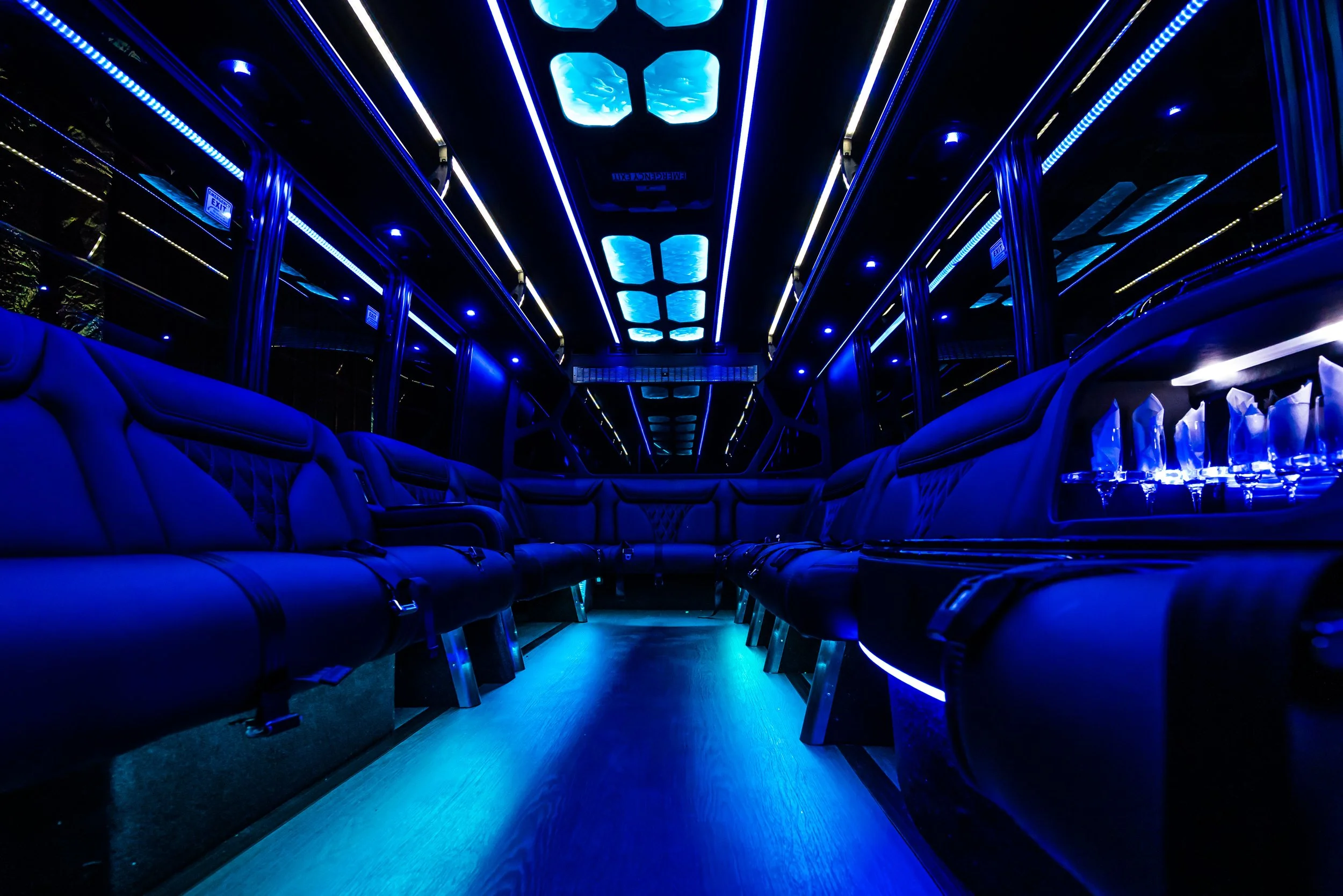 Interior of a luxury limousine with blue LED lighting and black leather seats.