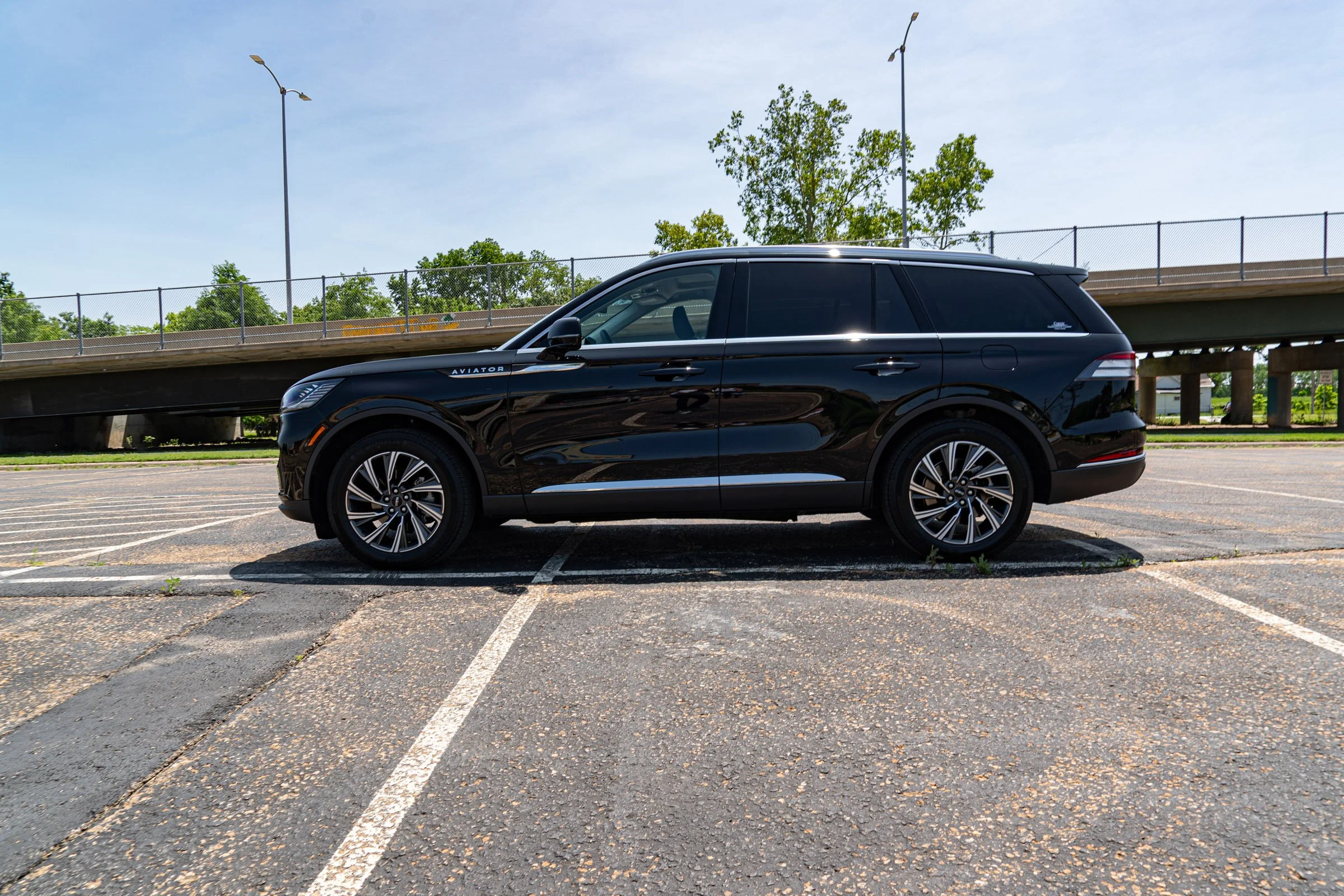 Black luxury SUV parked in an empty parking lot on a sunny day.