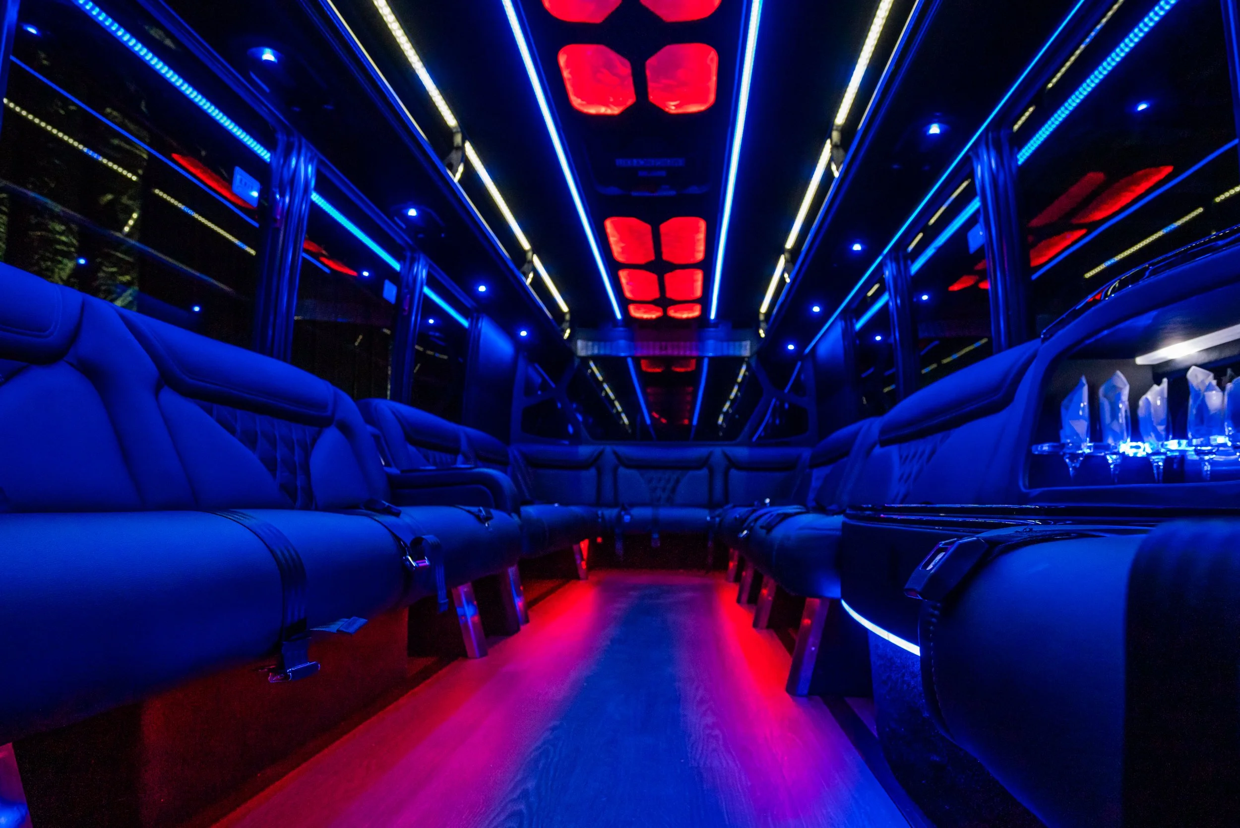 Inside a luxury bus with blue leather seats, mood lighting, and red ceiling lights.