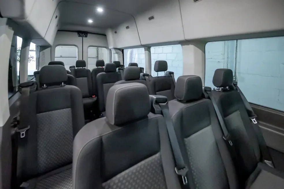 Interior of a passenger van with multiple black fabric seats arranged in rows.