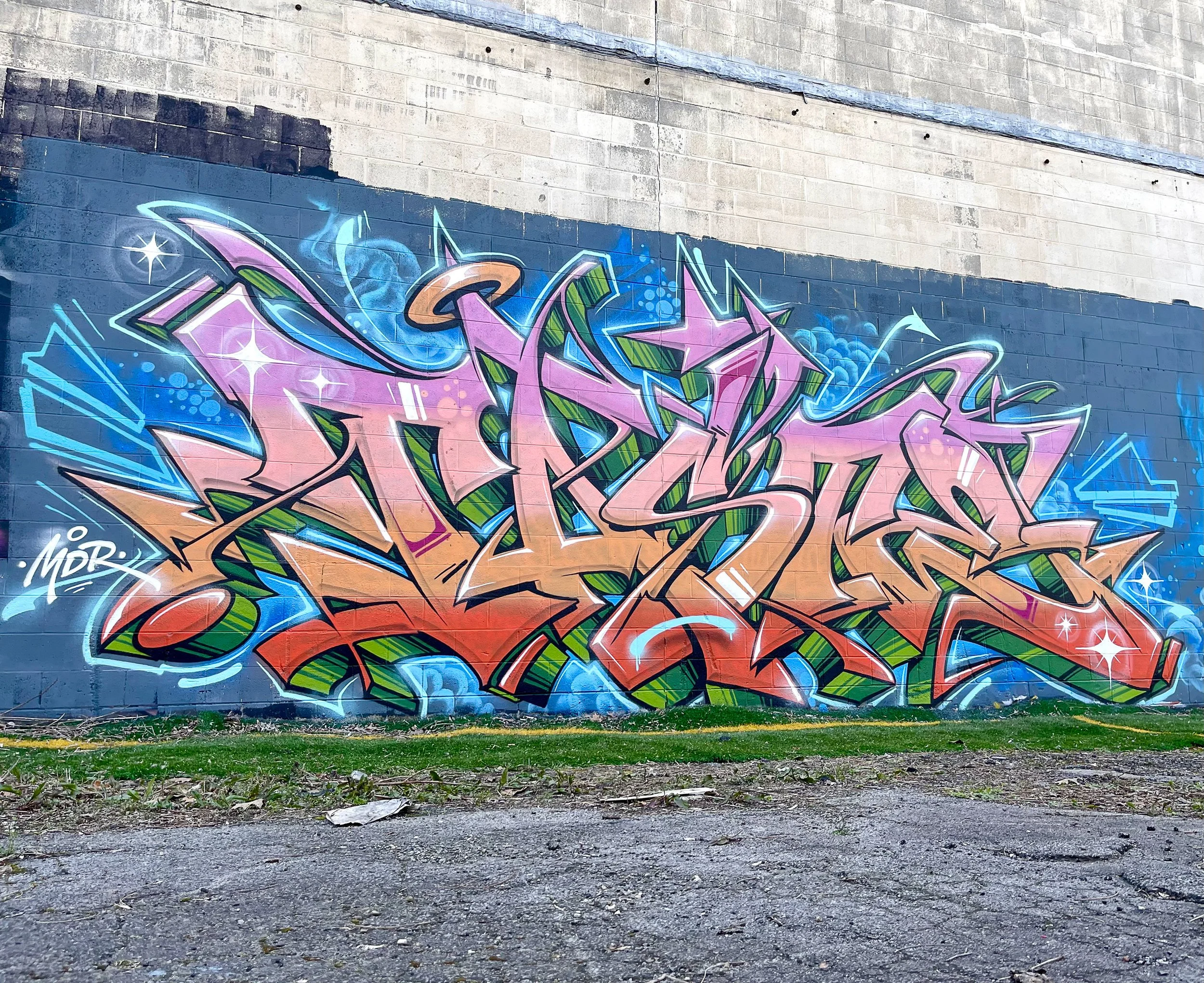 large colorful graffiti art mural on a brick wall in a parking lot