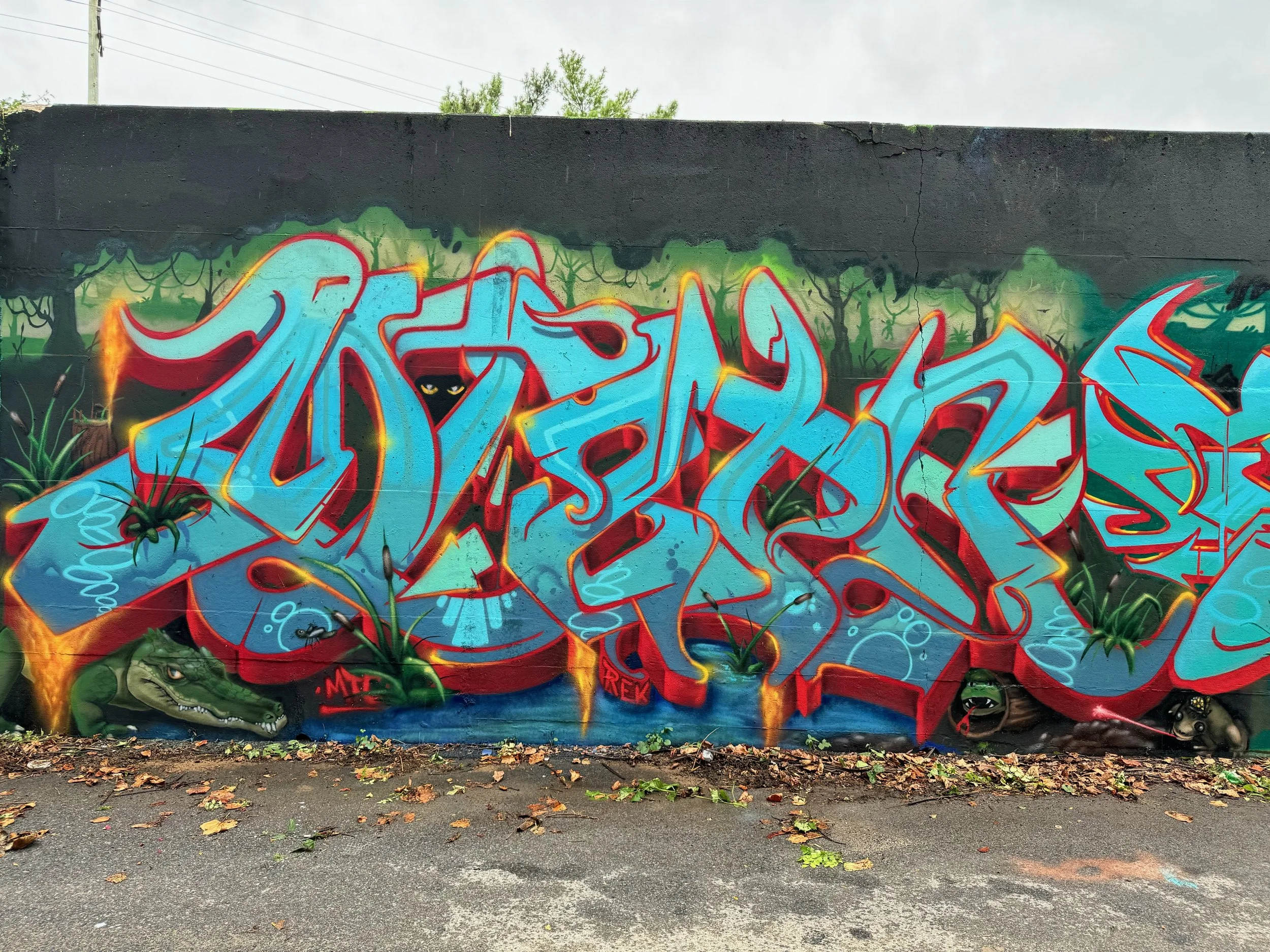 large vibrant graffiti art lettering mural of jungle themed art on concrete wall in alley