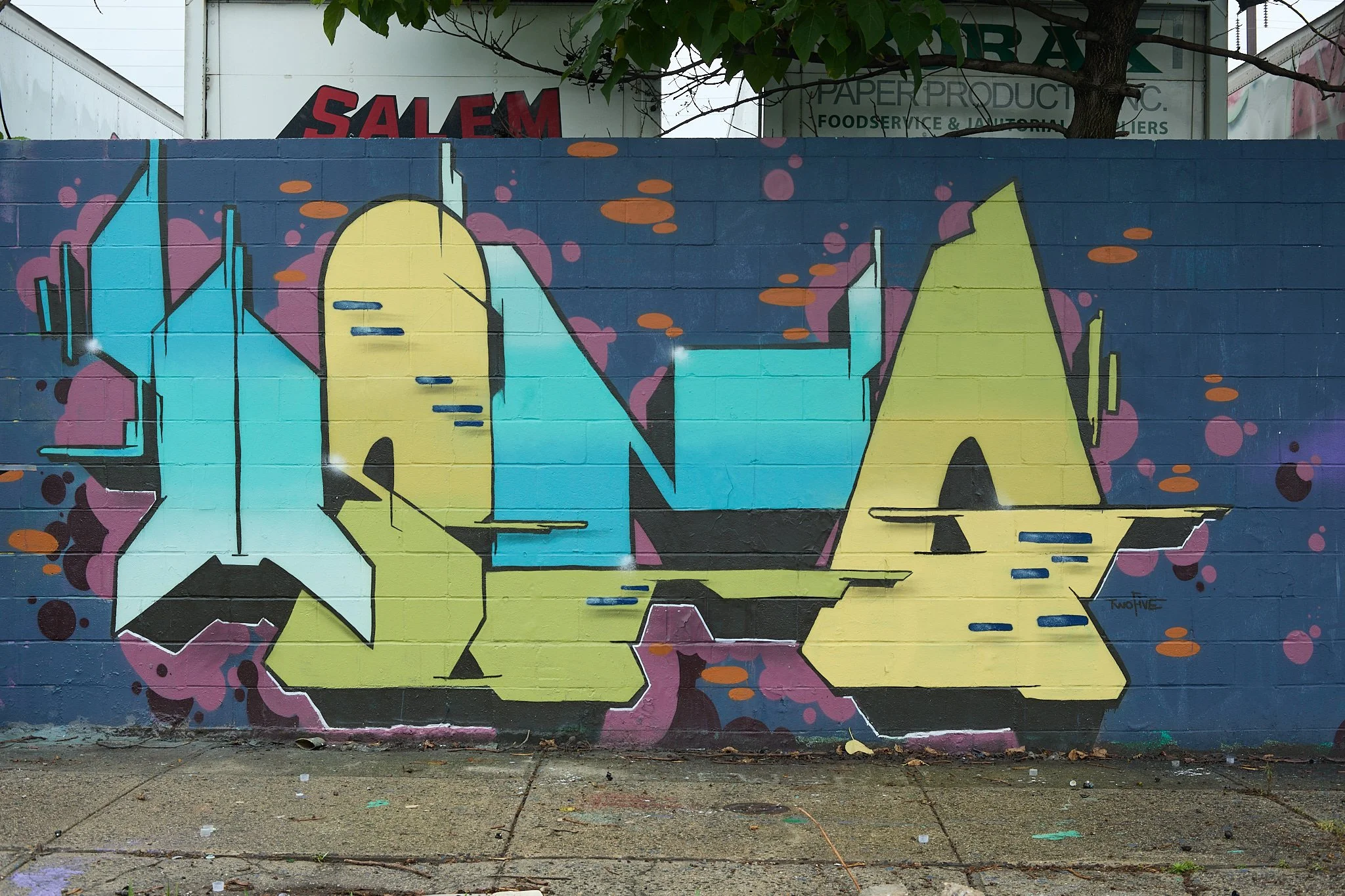 colorful graffiti mural on brick wall in front of trees