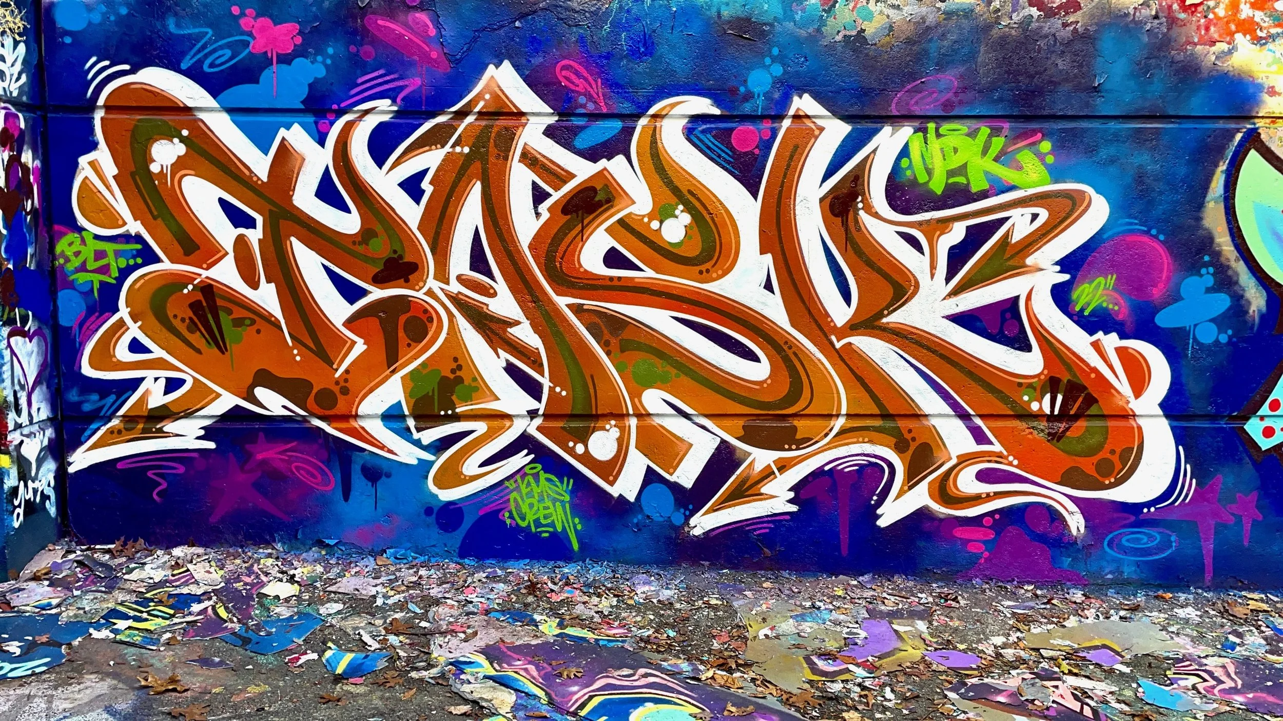 bold graffiti lettering mural on blue concrete wall