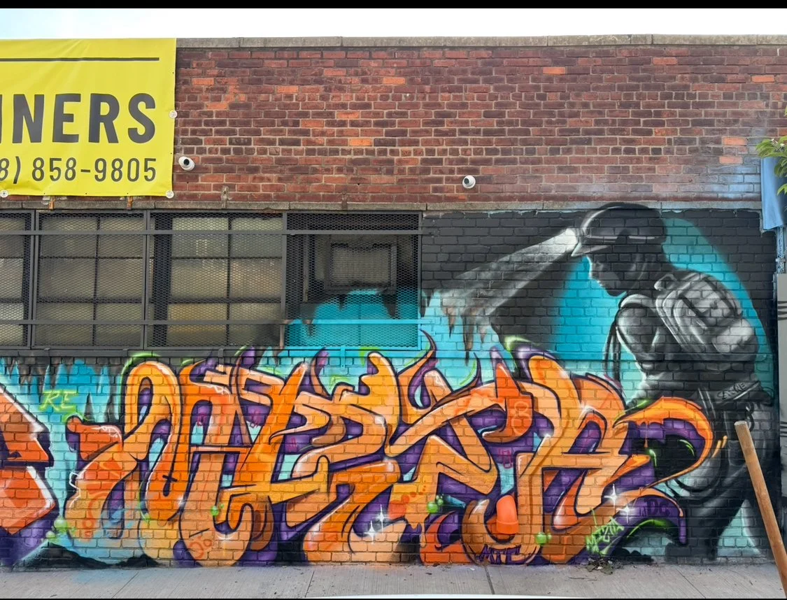 large graffiti lettering mural art fireman tribute art on brick wall on the side of building on busy street