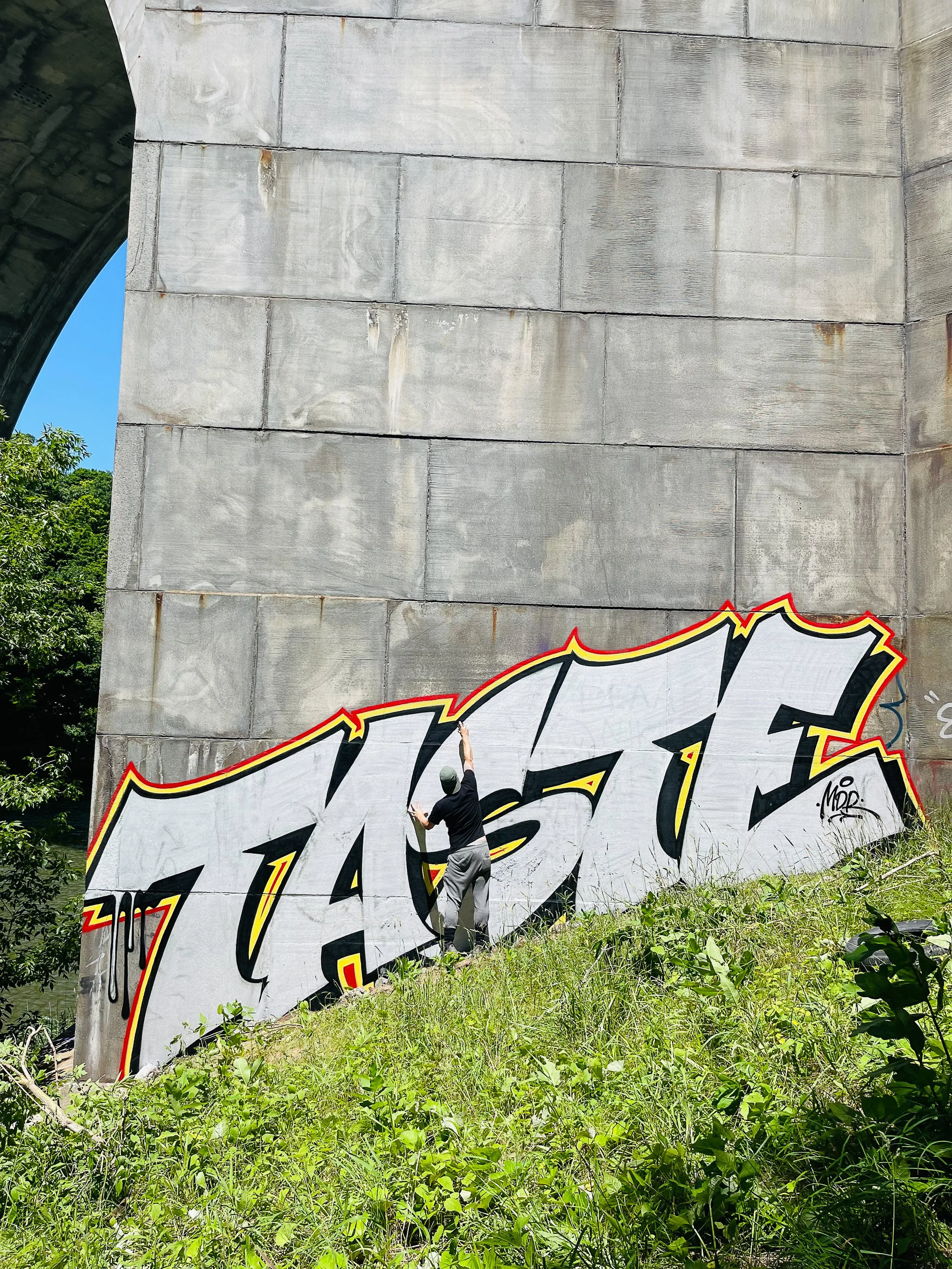 giant chrome graffiti lettering on bridge featuring artist for scale