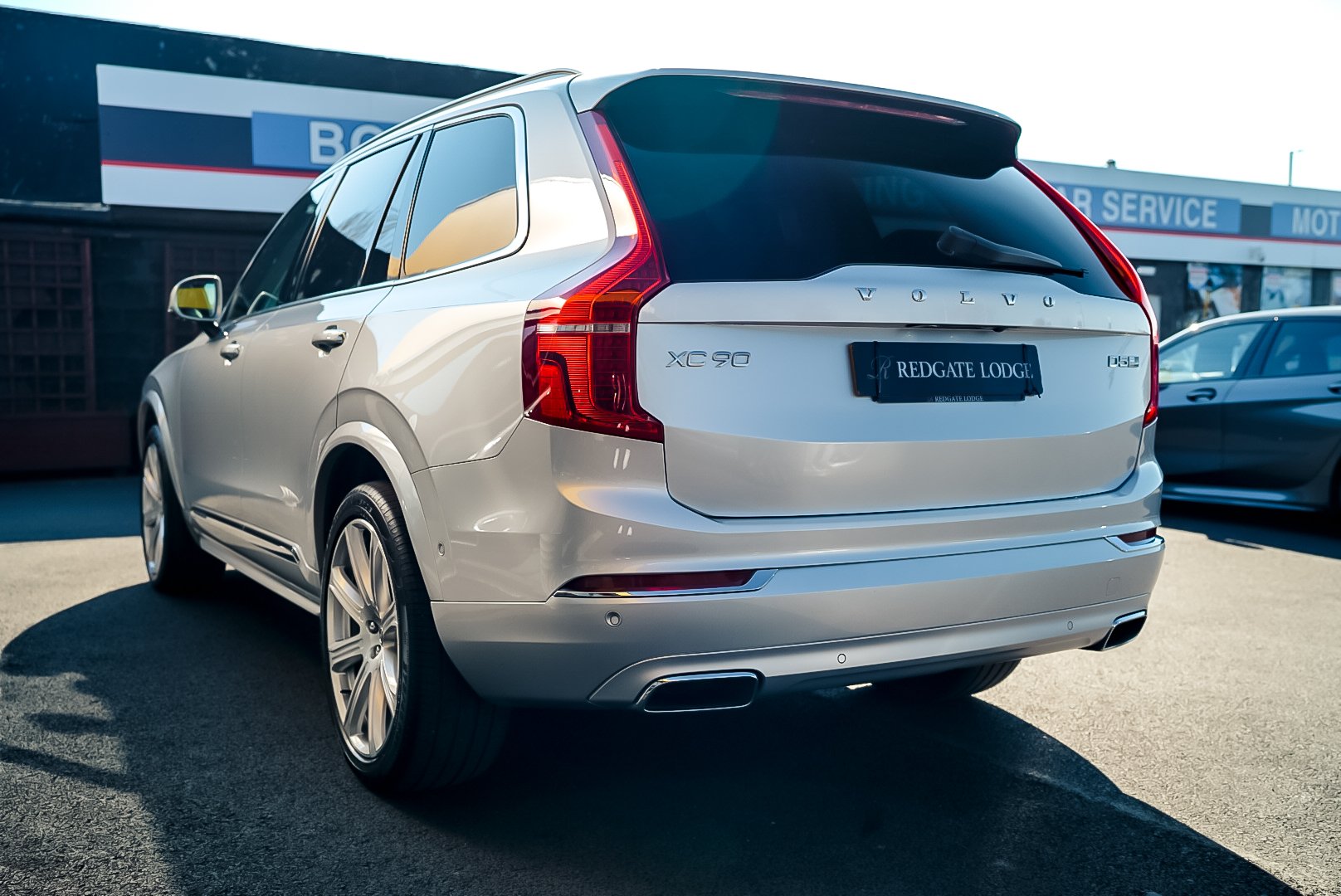 Rear view of a silver Volvo XC90 SUV in a parking lot.