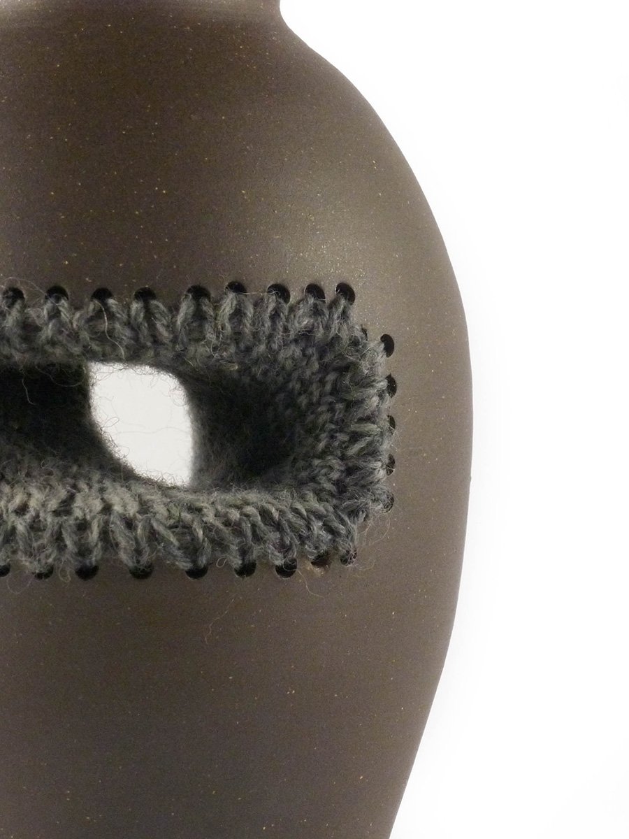 Close-up of brown ceramic vase with knitted texture