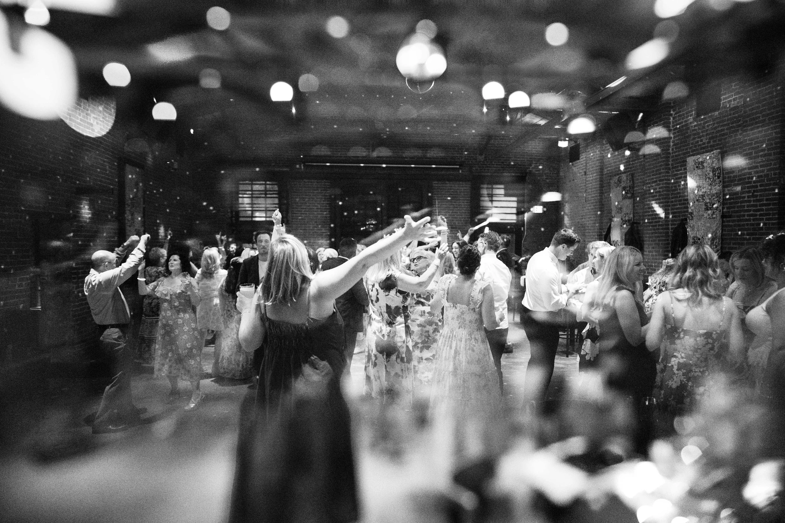 People dancing and socializing at a party or nightclub with brick walls and artistic decorations.