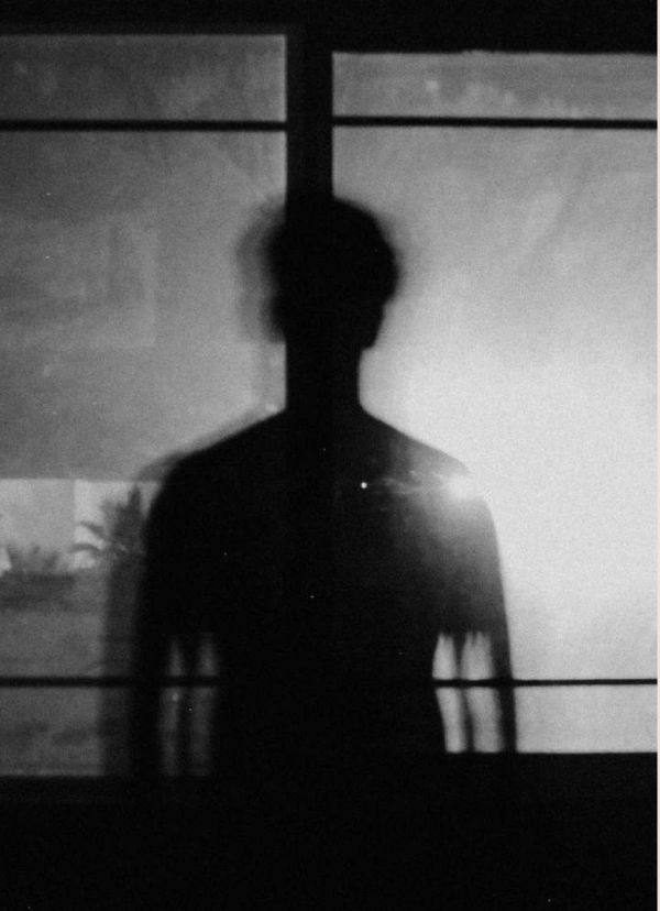 Silhouette of a person standing in front of a bright window