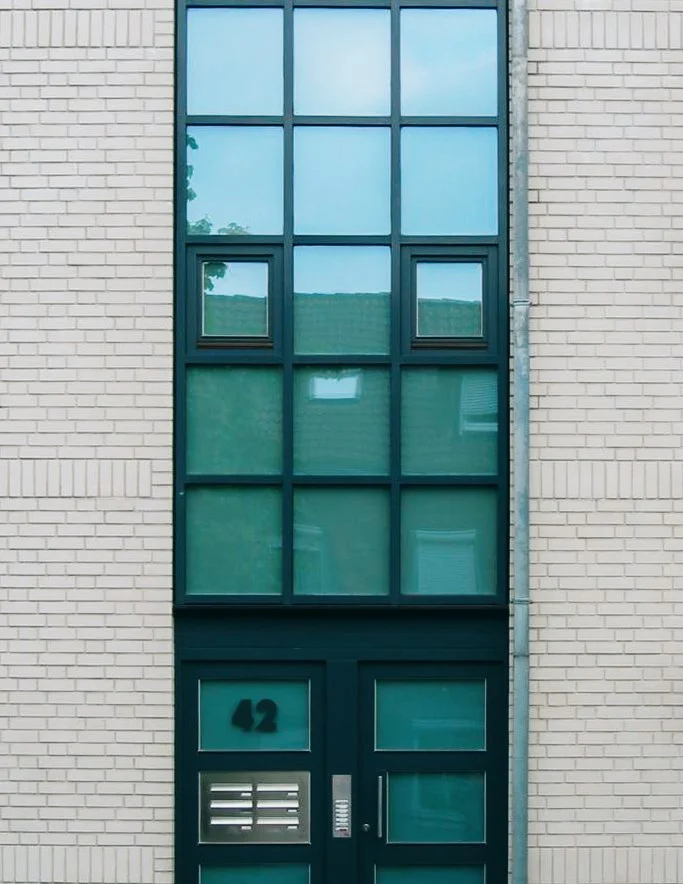 Mehrstöckiges modernes Gebäude mit großen Fenstern und einer Tür, die die Nummer 42 trägt.