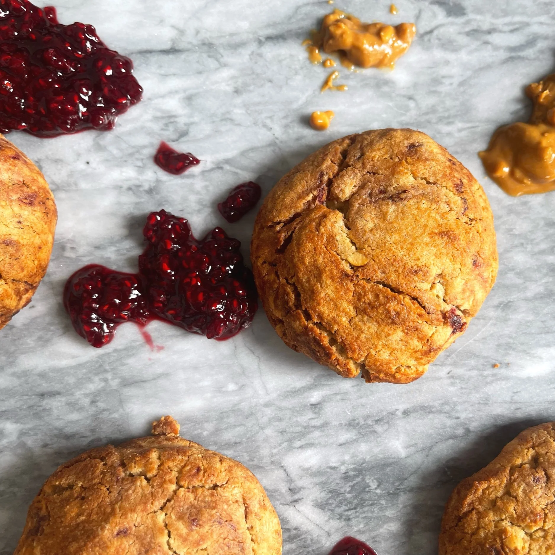 Doughish peanut butter and jam cookies on marble surface.