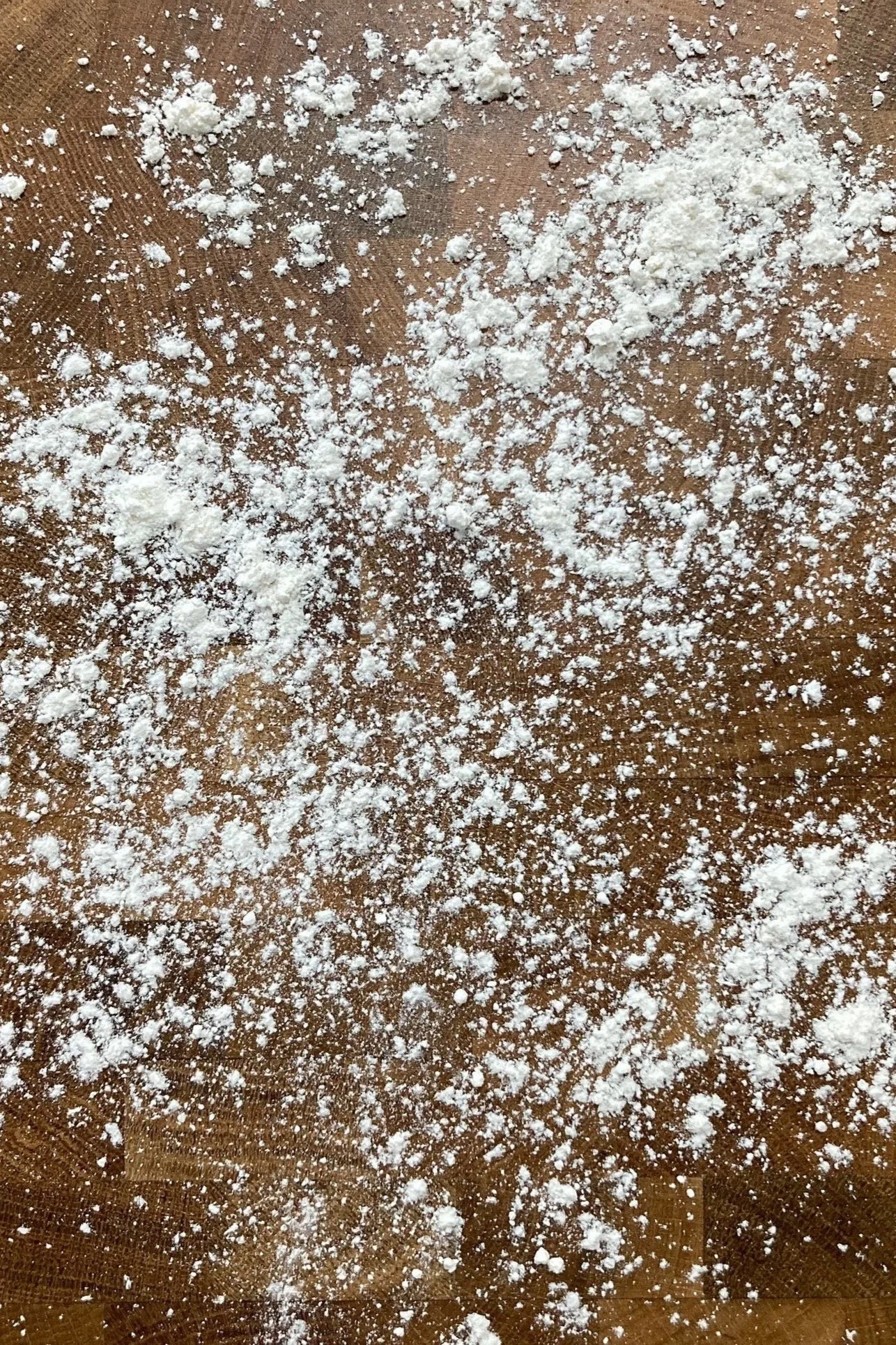 Powdered flour dusted on a brown wooden surface.