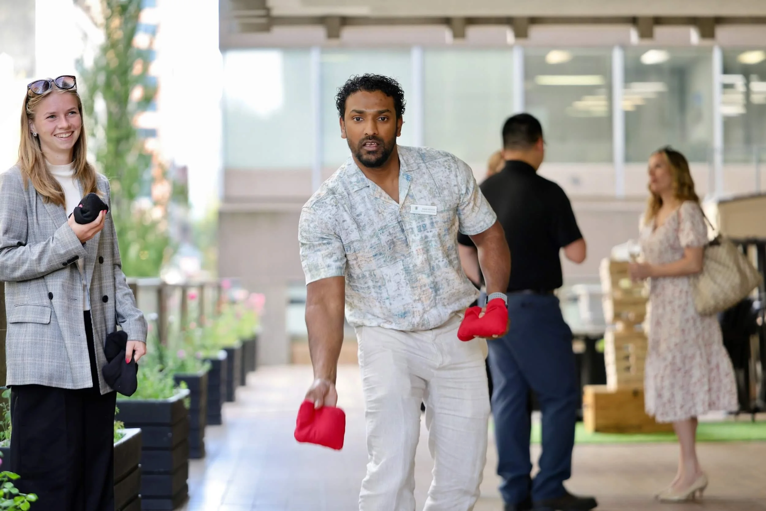Man throwing cornhole bag at corporate party while female co-worker looks on