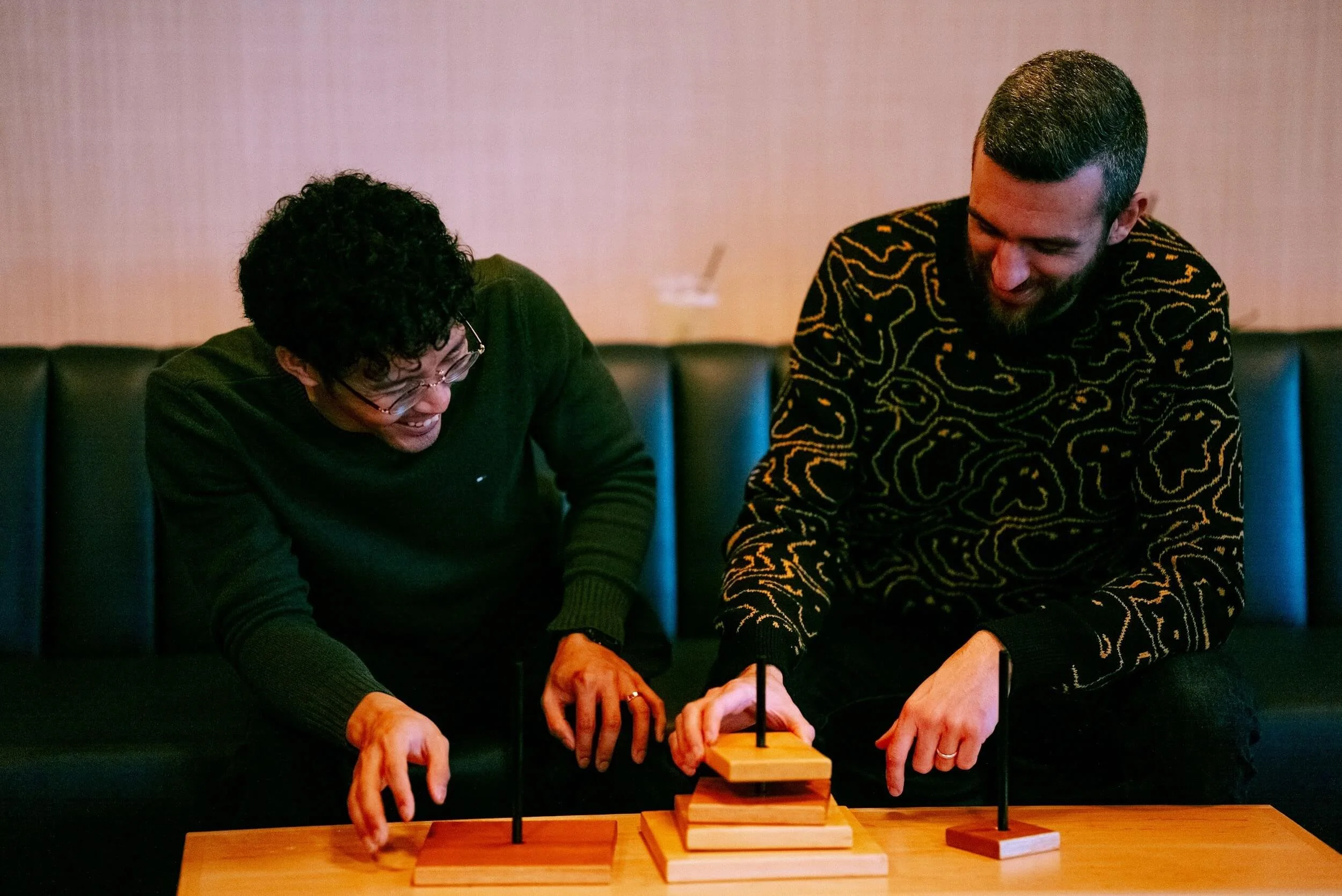 Two people playing the game of Tower of Hanoi