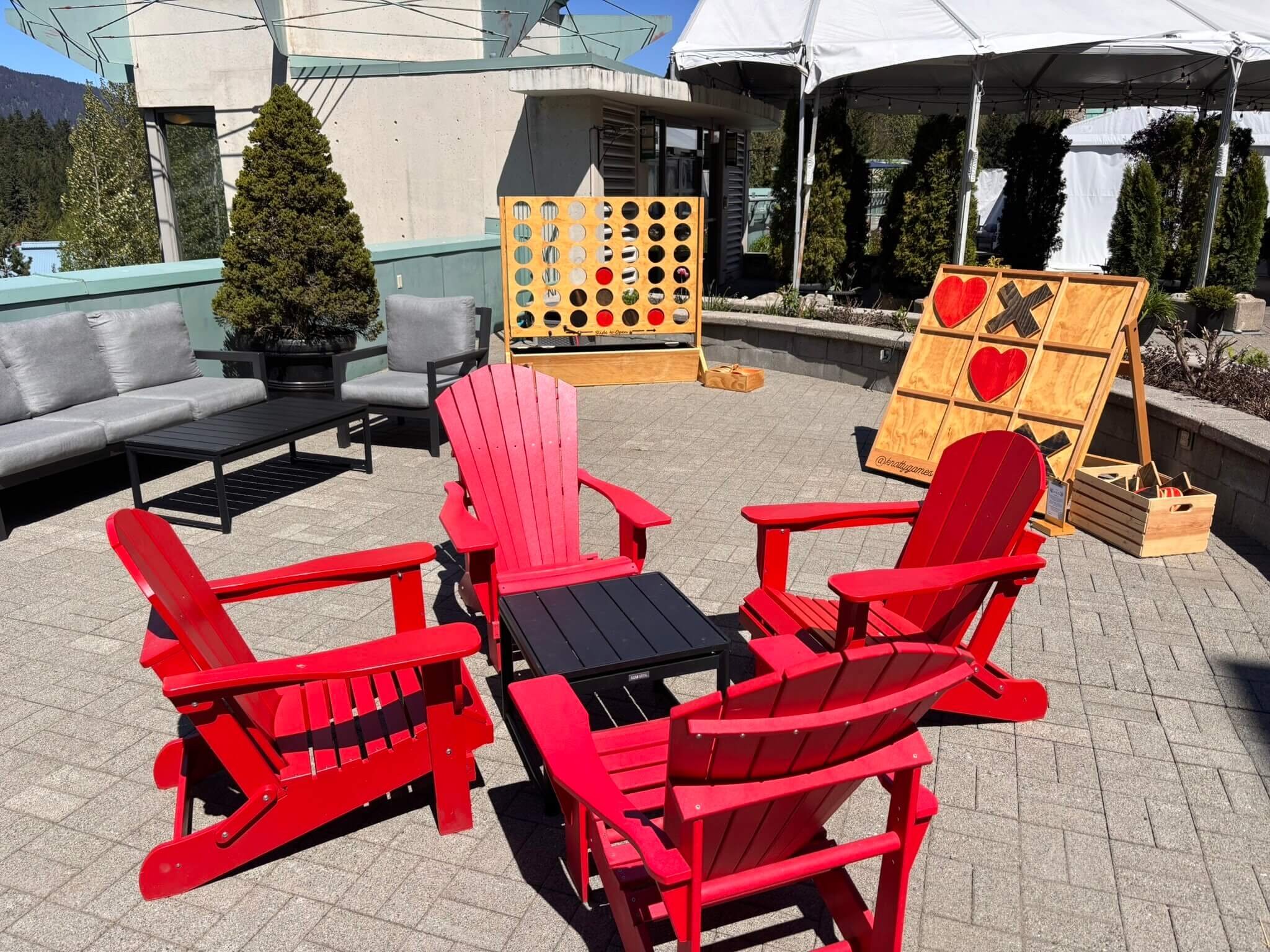 Seated area with red muskoka chairs and some games surrounding it