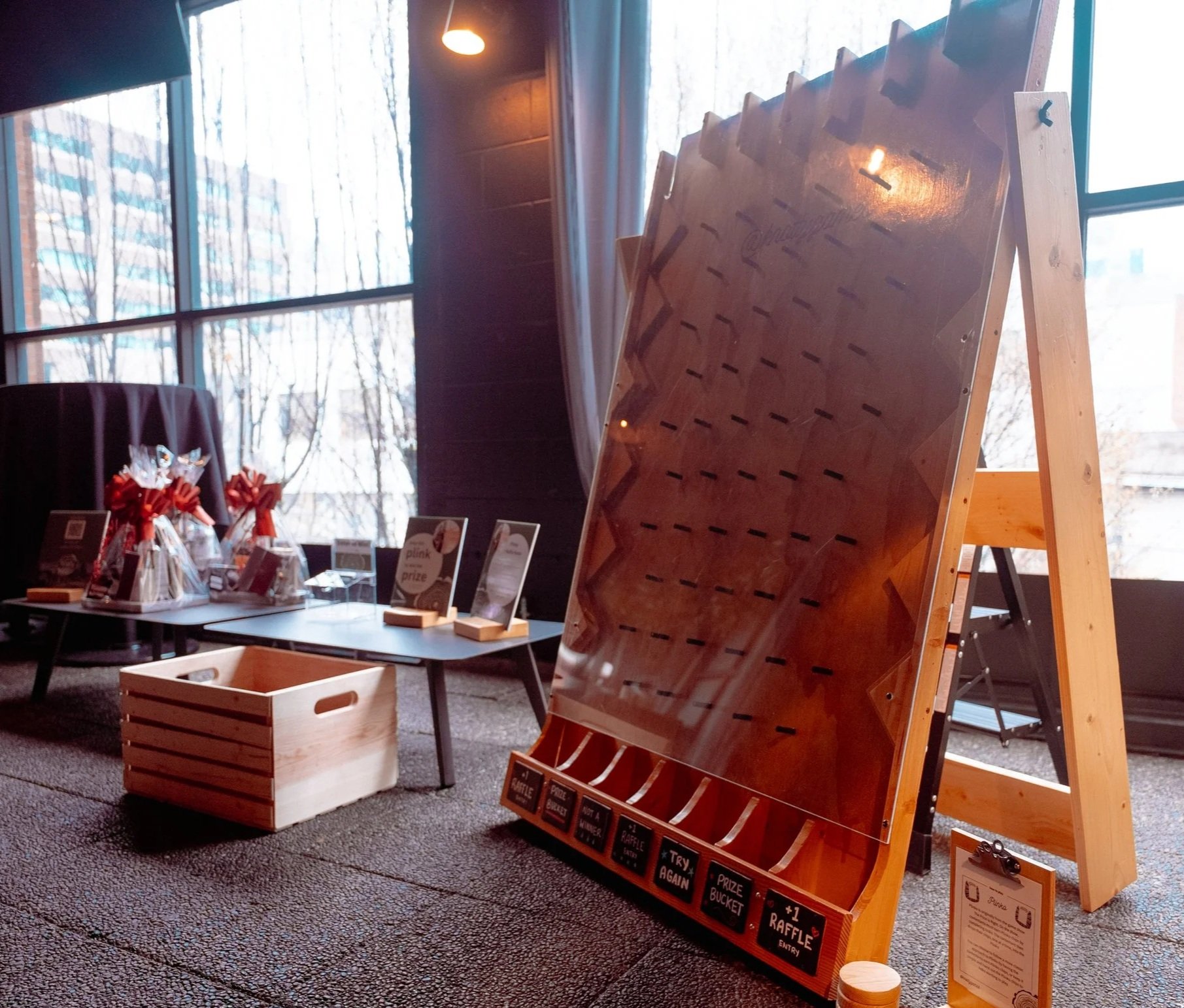 A plinko board at a wedding with customized pockets at the bottom, sitting next to raffle prize options.
