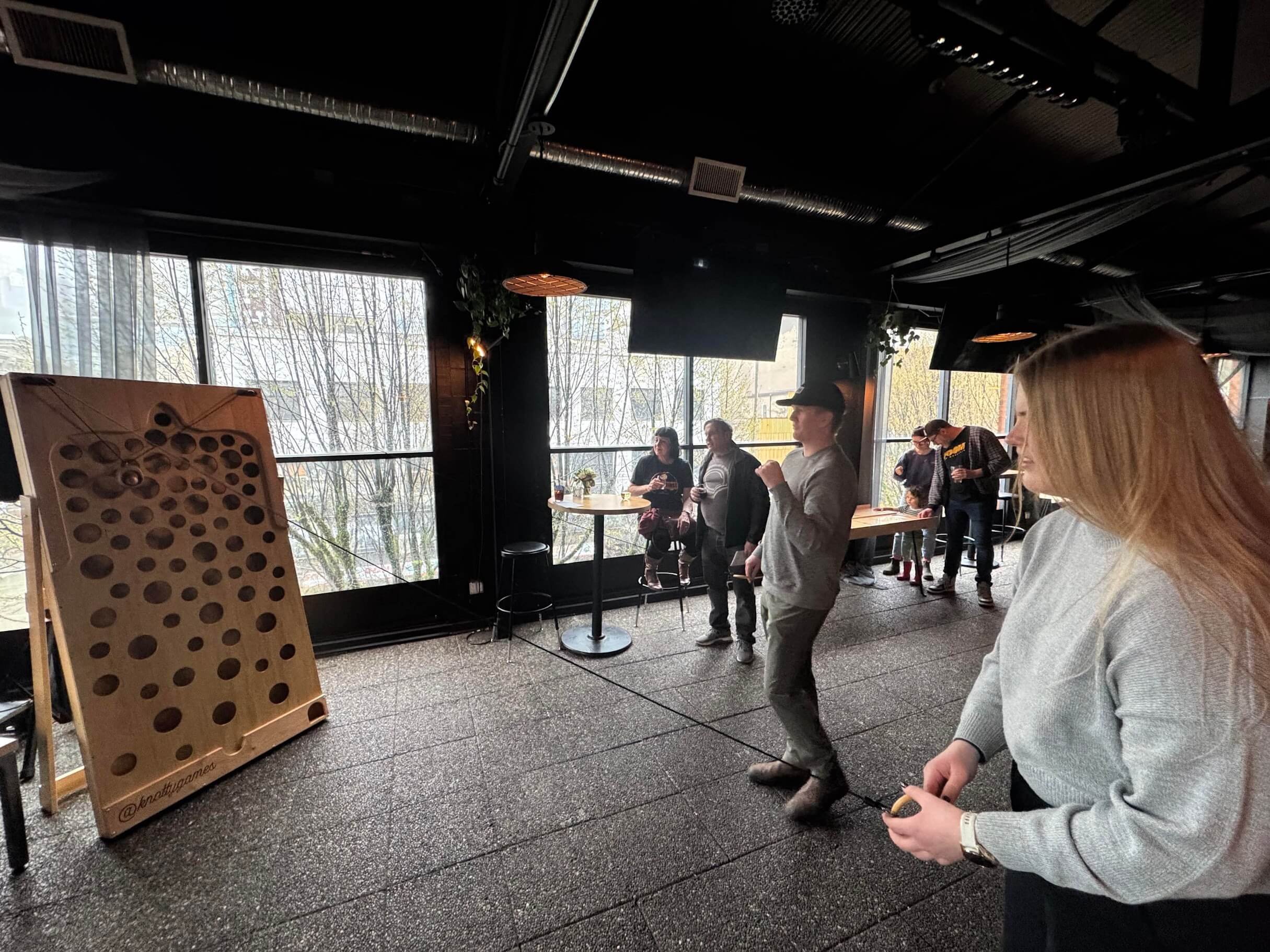 One person playing a Wall Ball Maze Game while people look on.