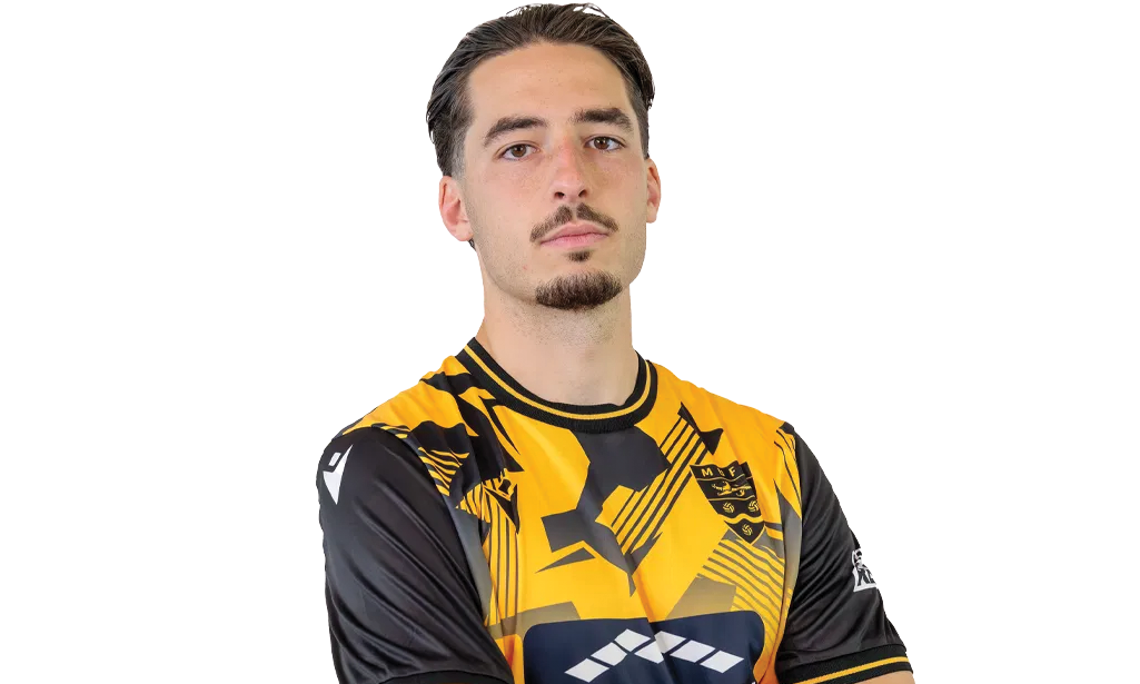 A young man with dark hair and a goatee standing with arms crossed, wearing a yellow and black sports jersey with a logo on the chest and sleeves, against a white background.