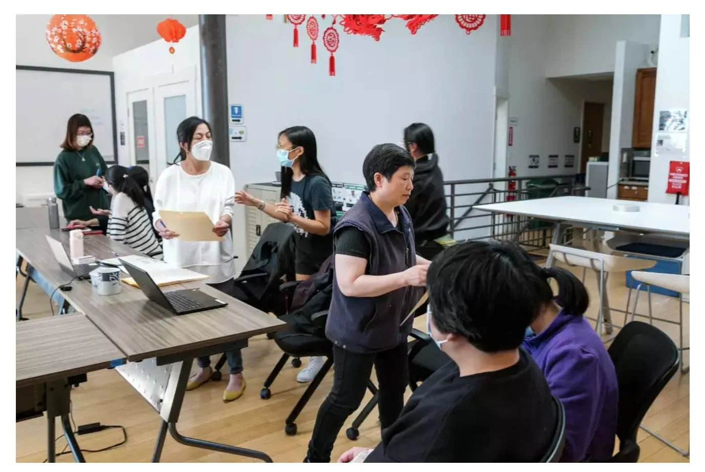 A group of people are gathered around in an office space talking.