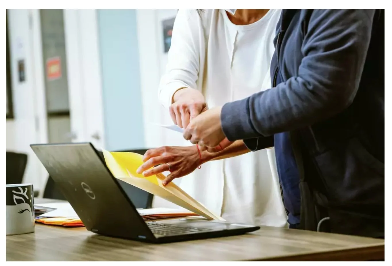 Two sets of hands holding a piece of paper and an envelope.