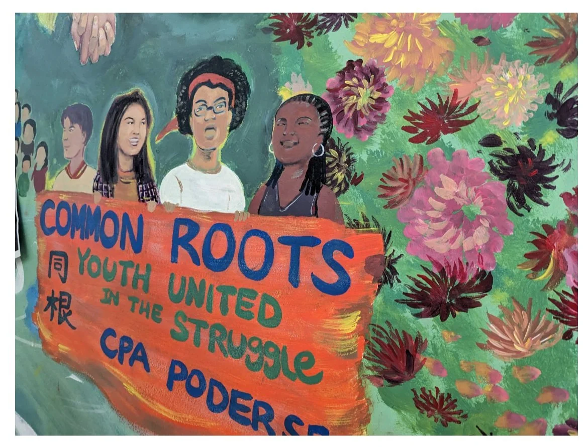 A mural depicting activists holding up a banner saying common roots youth united in the struggle