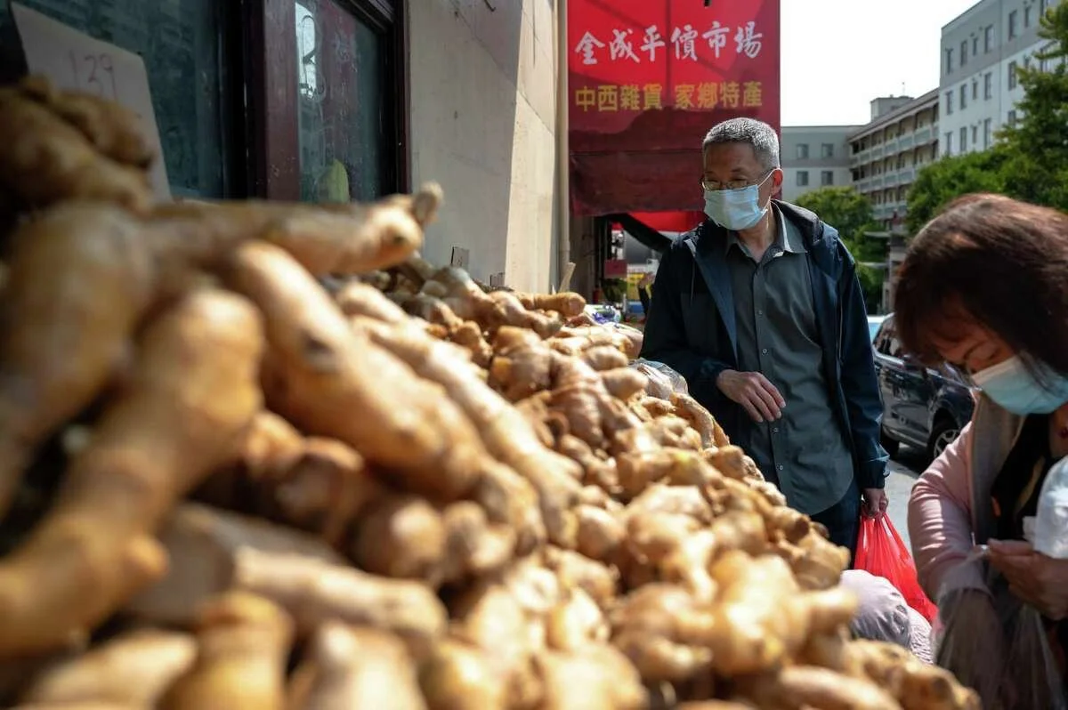 A man with a face mask looking at some ginger.