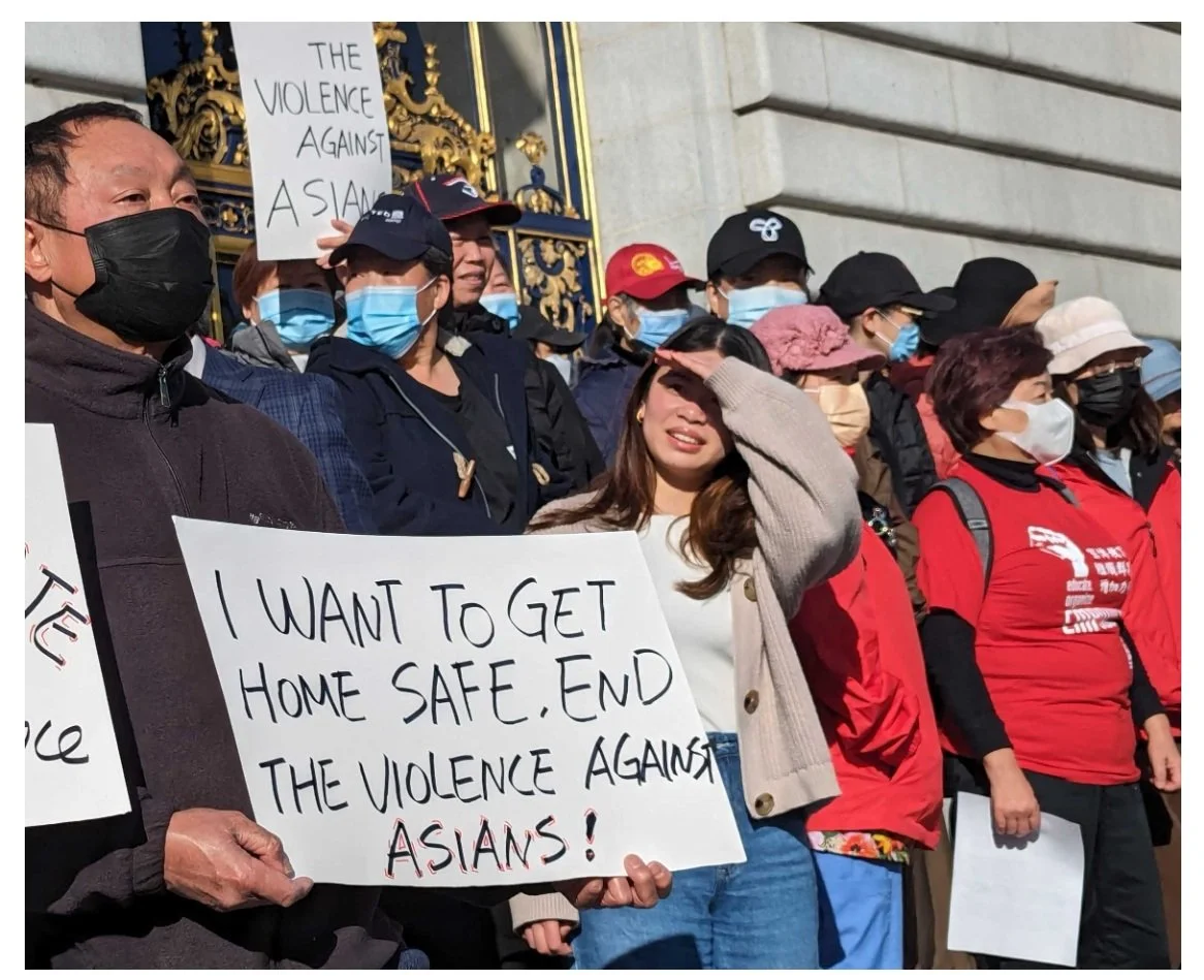 Protestors in masks holding up a sign that says "I want to get home safe, end the violence against Asians!"